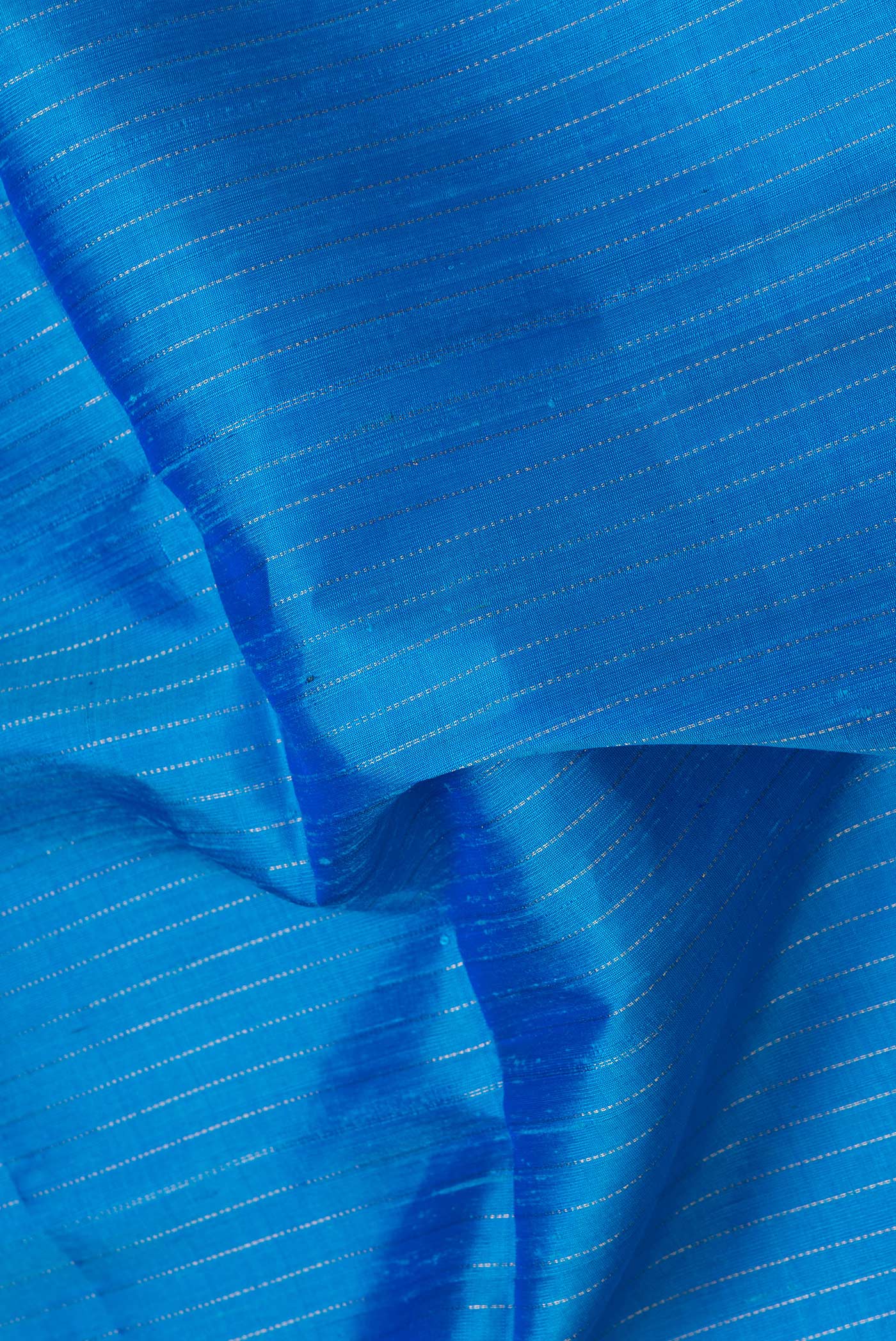 Close up of Sky Blue Dual Tone Raw Silk Saree with Stripes on the body and Thin Zari Line.  displaying folds