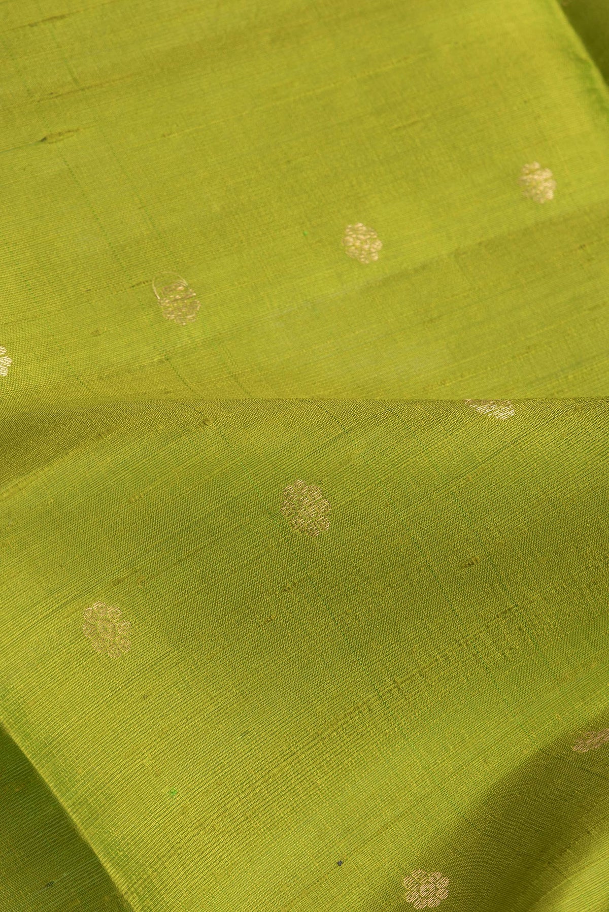 Close up of Parrot Green Dual Tone Raw Silk Saree with Zari Butta on the body and Zari Border.  displaying folds