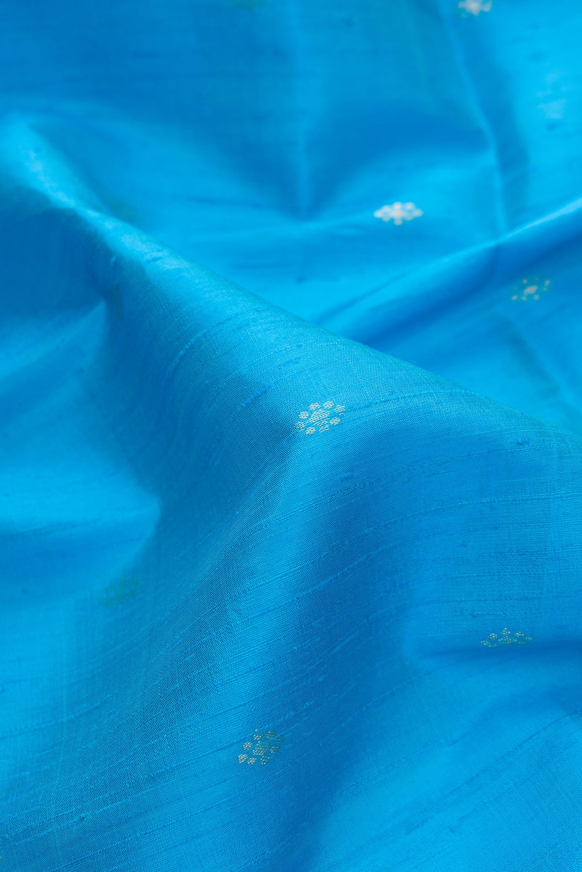 Close up of Sky Blue Dual Tone Raw Silk Saree with Zari Butta on the body and Zari Border.  displaying folds