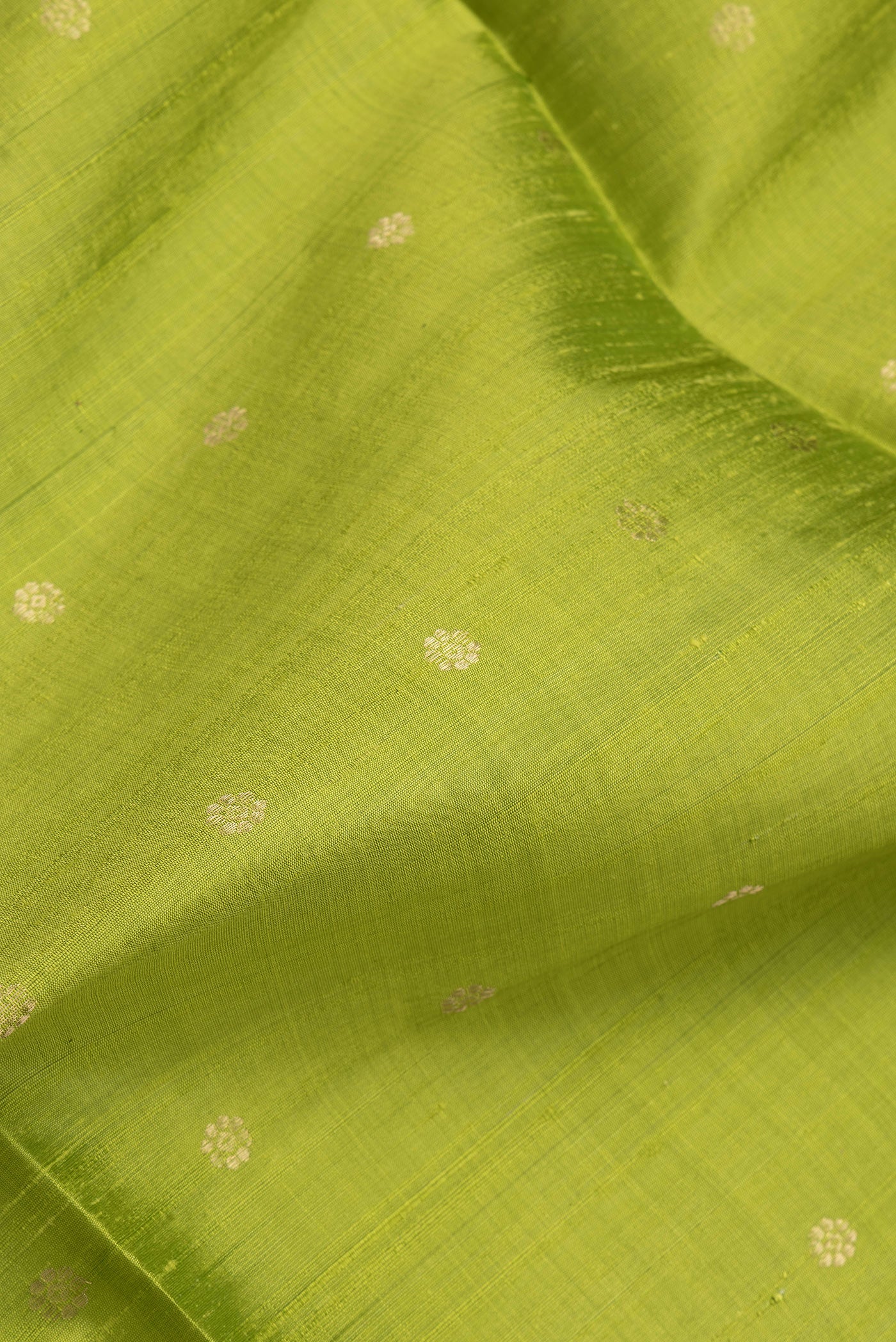 Close up of Parrot Green Dual Tone Raw Silk Saree with Zari Butta on the body and Zari Border.  displaying folds