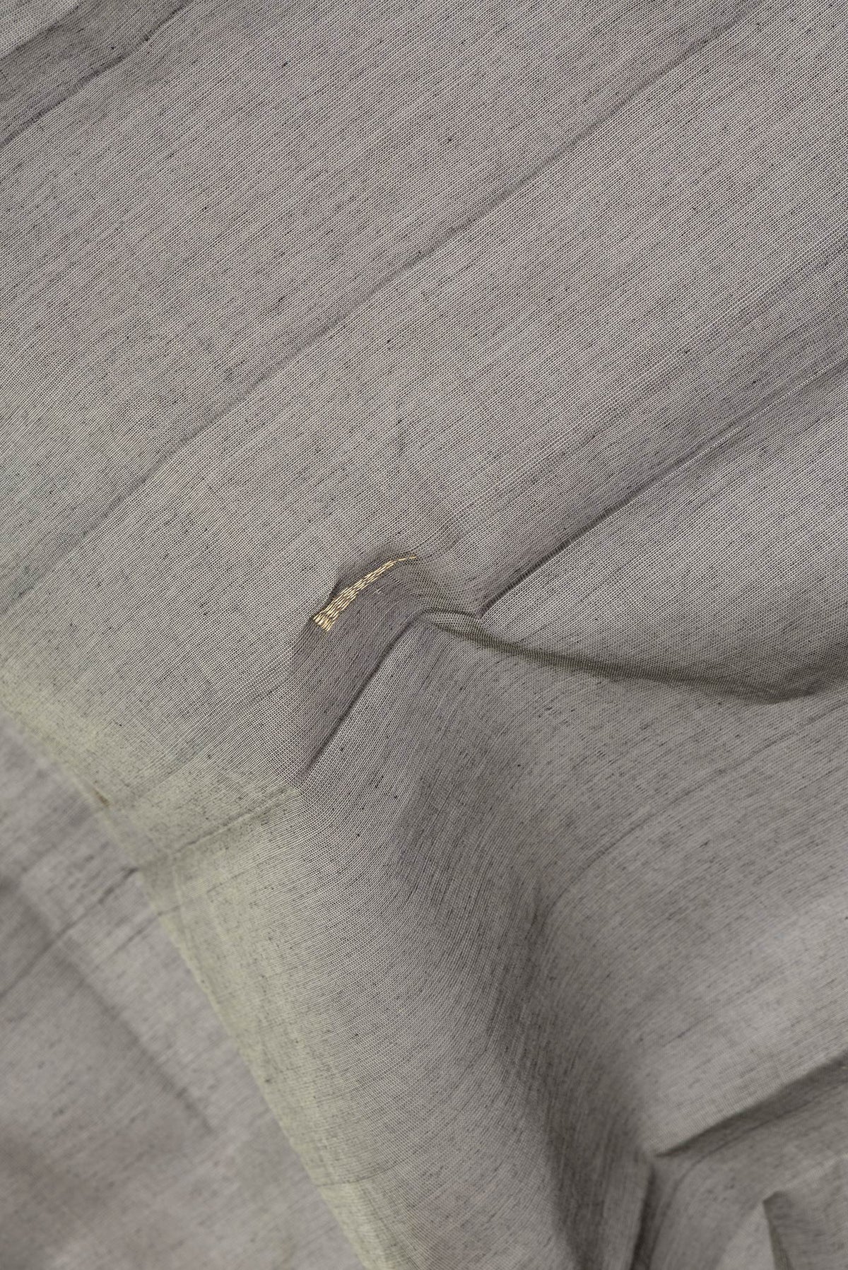 Close up of Grey Kanchi Cotton Saree with Zari Butta on the body and Zari Border.  displaying folds