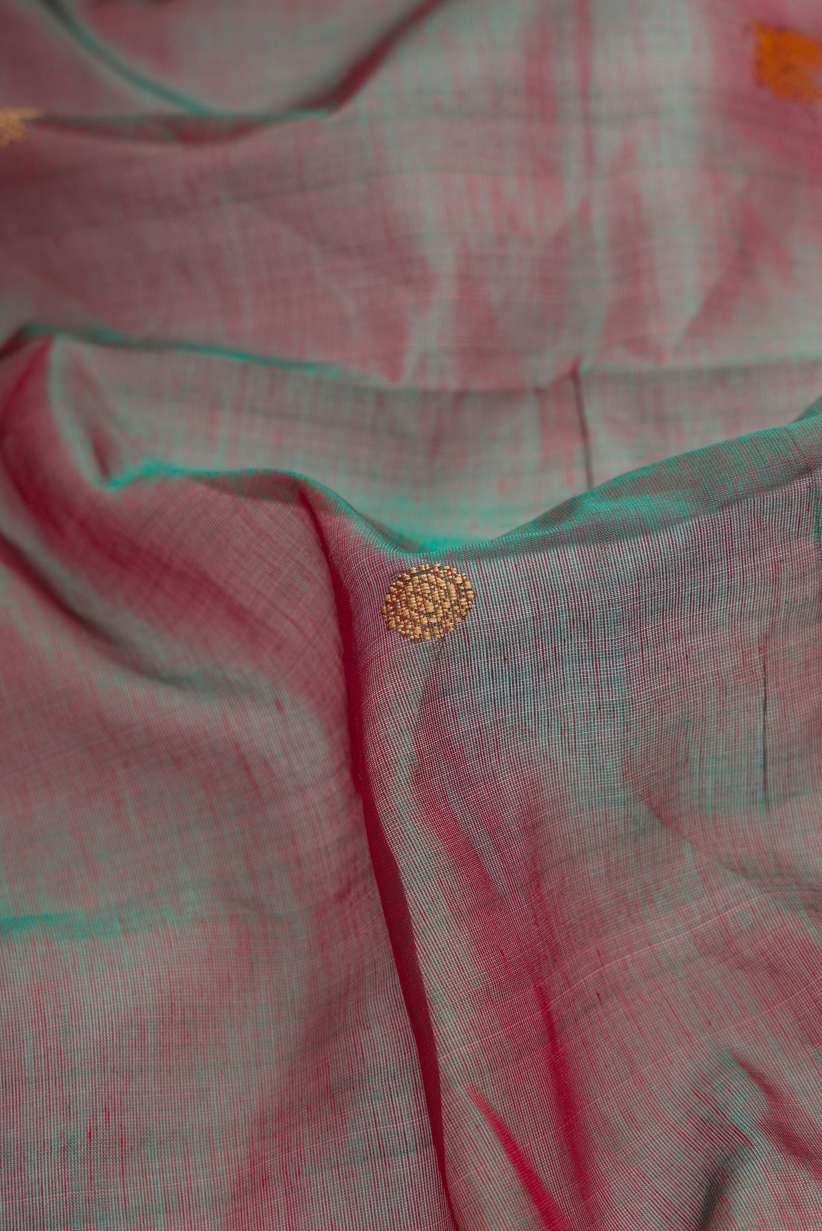 Close up of Red Dual Tone Silk Cotton Saree with Thread Butta on the body and Zari Border.  displaying folds