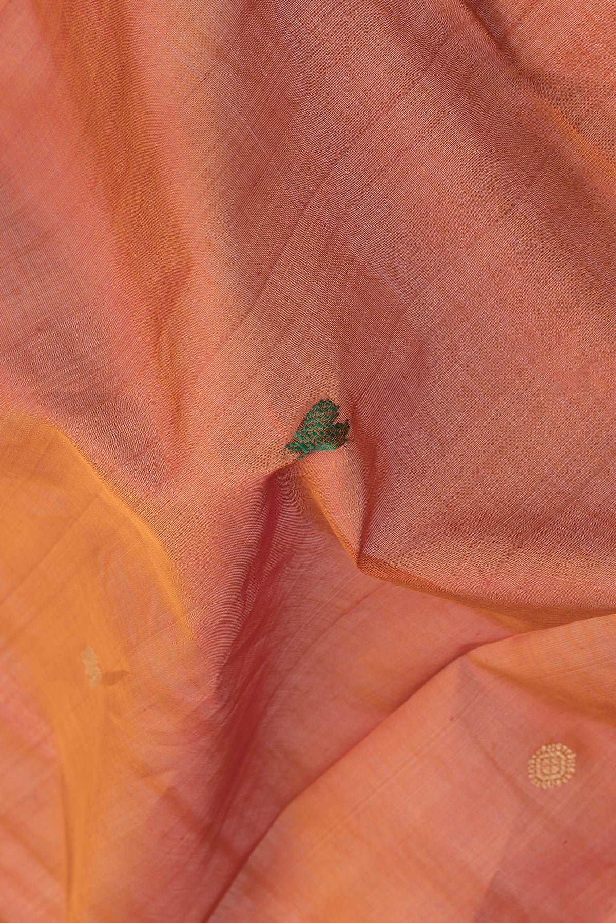 Close up of Brick Orange Dual Tone Silk Cotton Saree with Thread Butta on the body and Thread Border.  displaying folds