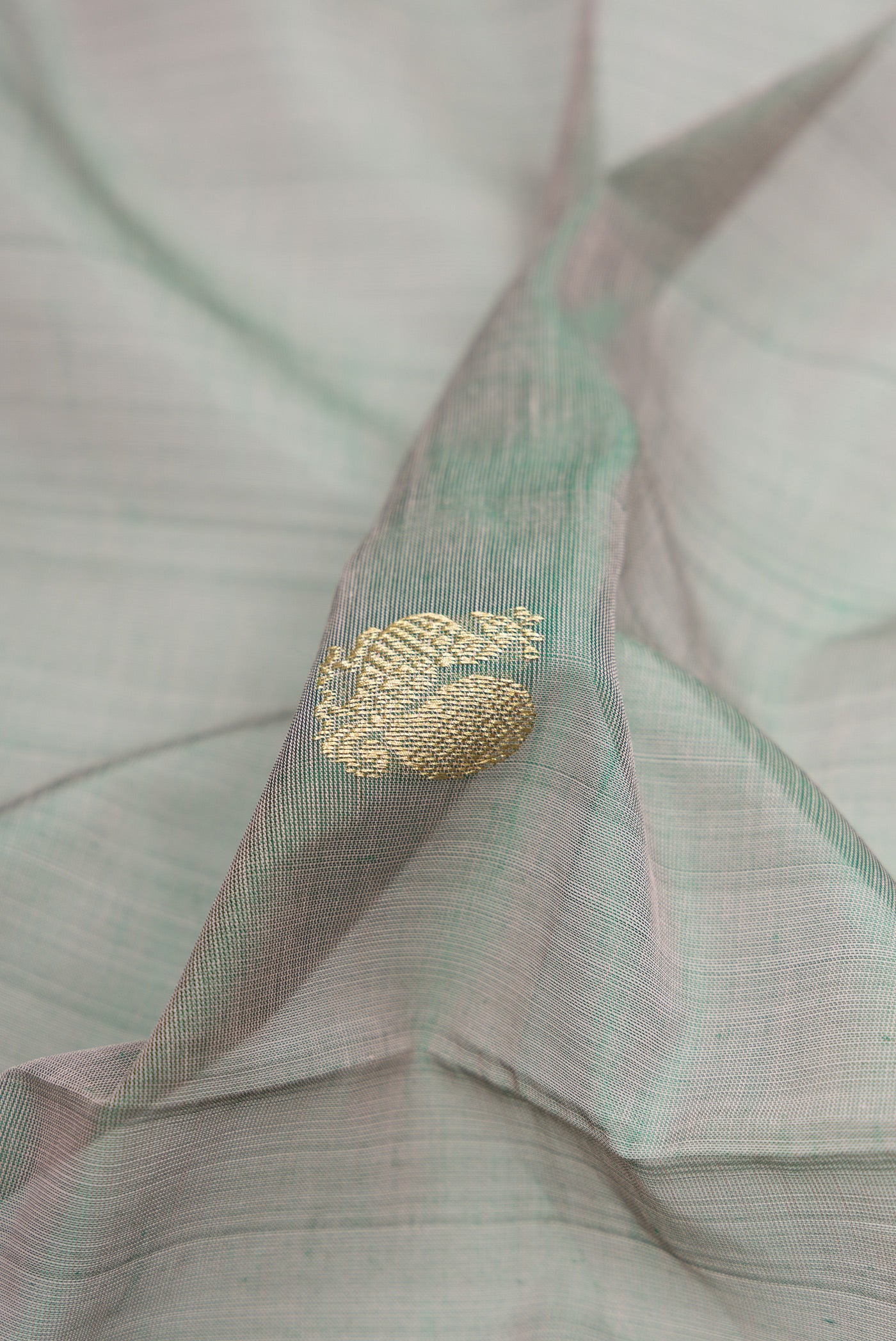 Close up of Grey with Green Color Silk Cotton Saree with Zari Butta on the body and Zari Border.  displaying folds