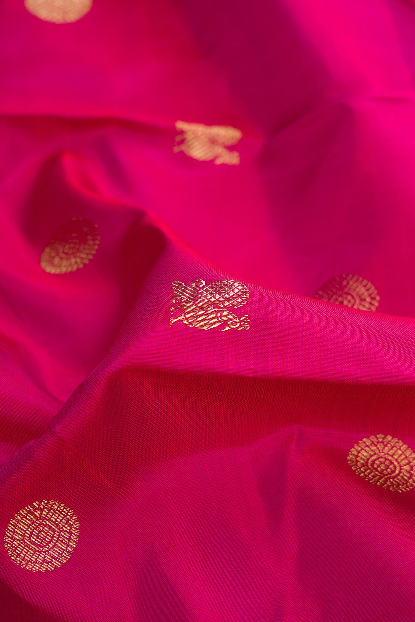 Close up of Pure Silk Pure Zari Magenta Dual Tone Kanchipuram Saree with Zari Butta on the body and Zari Border.  displaying folds