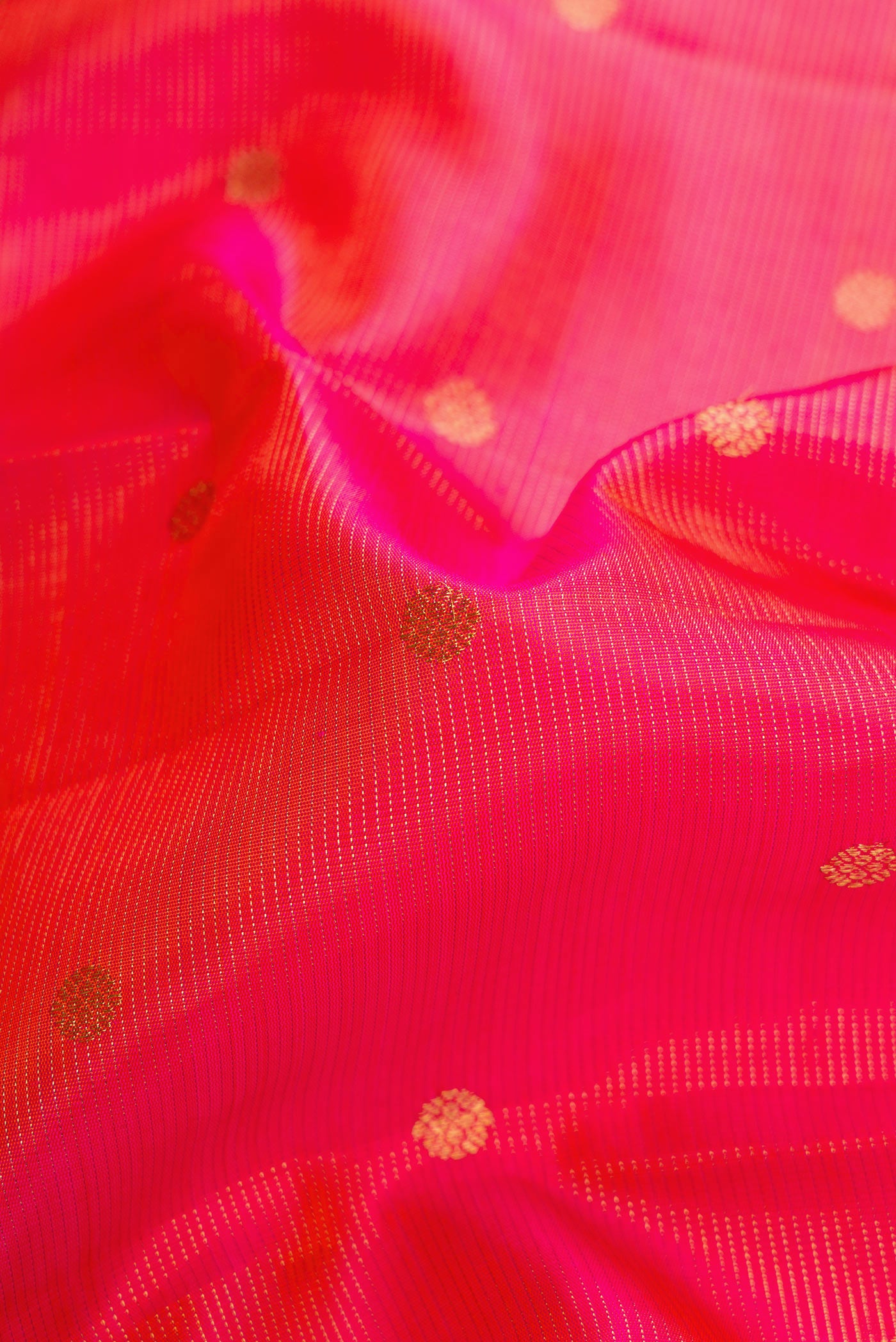 Close up of Coral Dual Tone Kanjivaram Silk Saree with Zari Butta on the body and Zari Border.  displaying folds