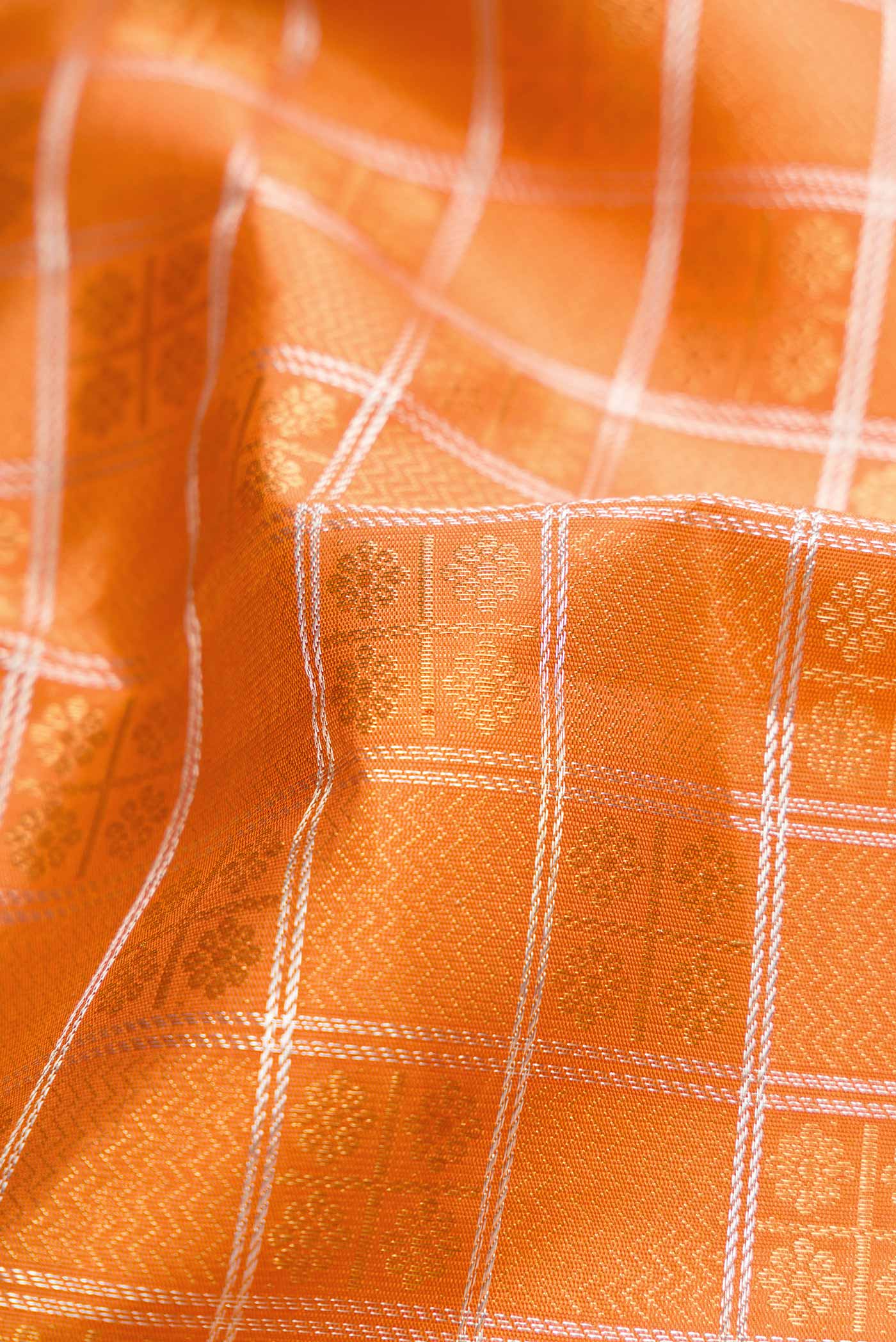 Close up of Pure Silk Pure Zari Orange Dual Tone Kanchipuram Saree with Zari Brocade on the body and Zari Border displaying folds