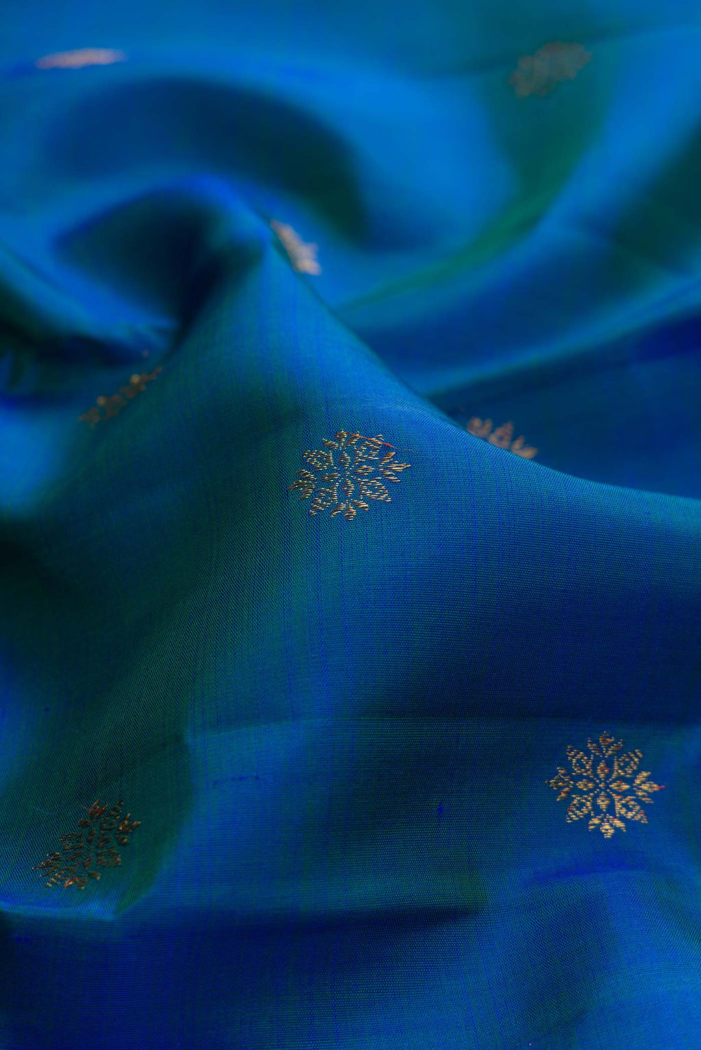 Close up of Pure Silk Pure Zari Peacock Blue Dual Tone Kanchipuram Saree with Zari Butta on the body and Zari Border displaying folds