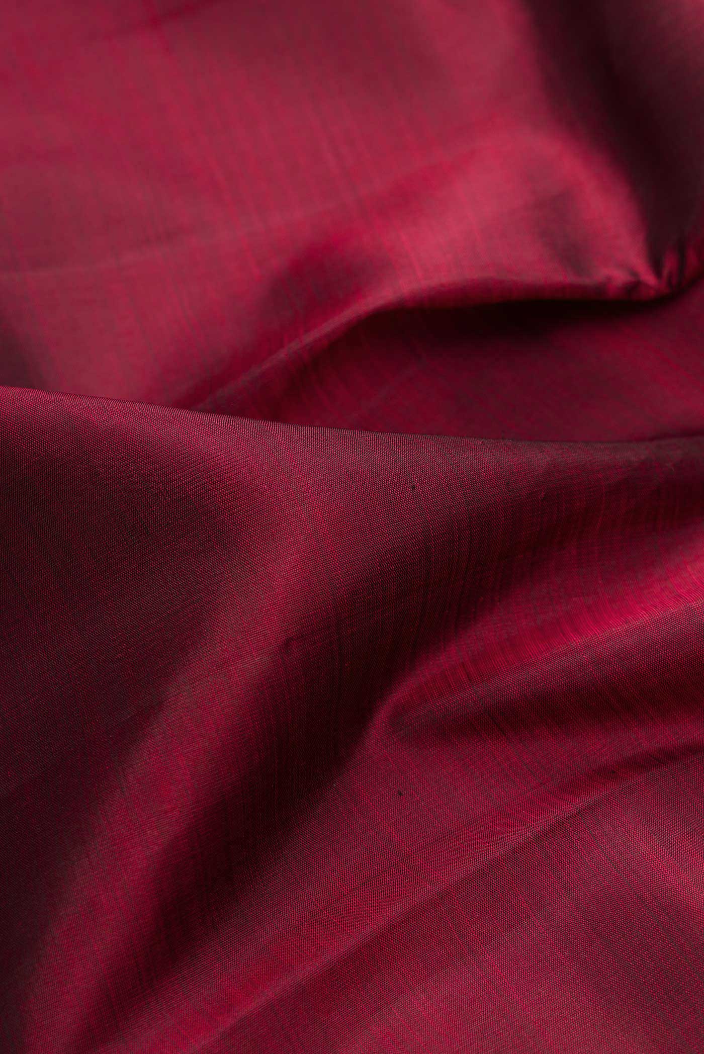 Close up of Maroon Dual Tone Kanjivaram Silk Saree with Plain Body and Thread Border.  displaying folds