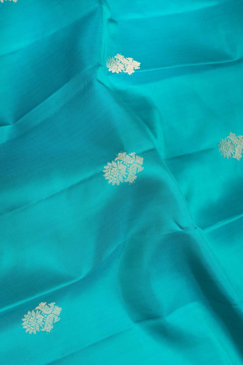 Close up of Green Dual Tone Kanjivaram Silk Saree with Zari Butta on the body and Zari Border.  displaying folds