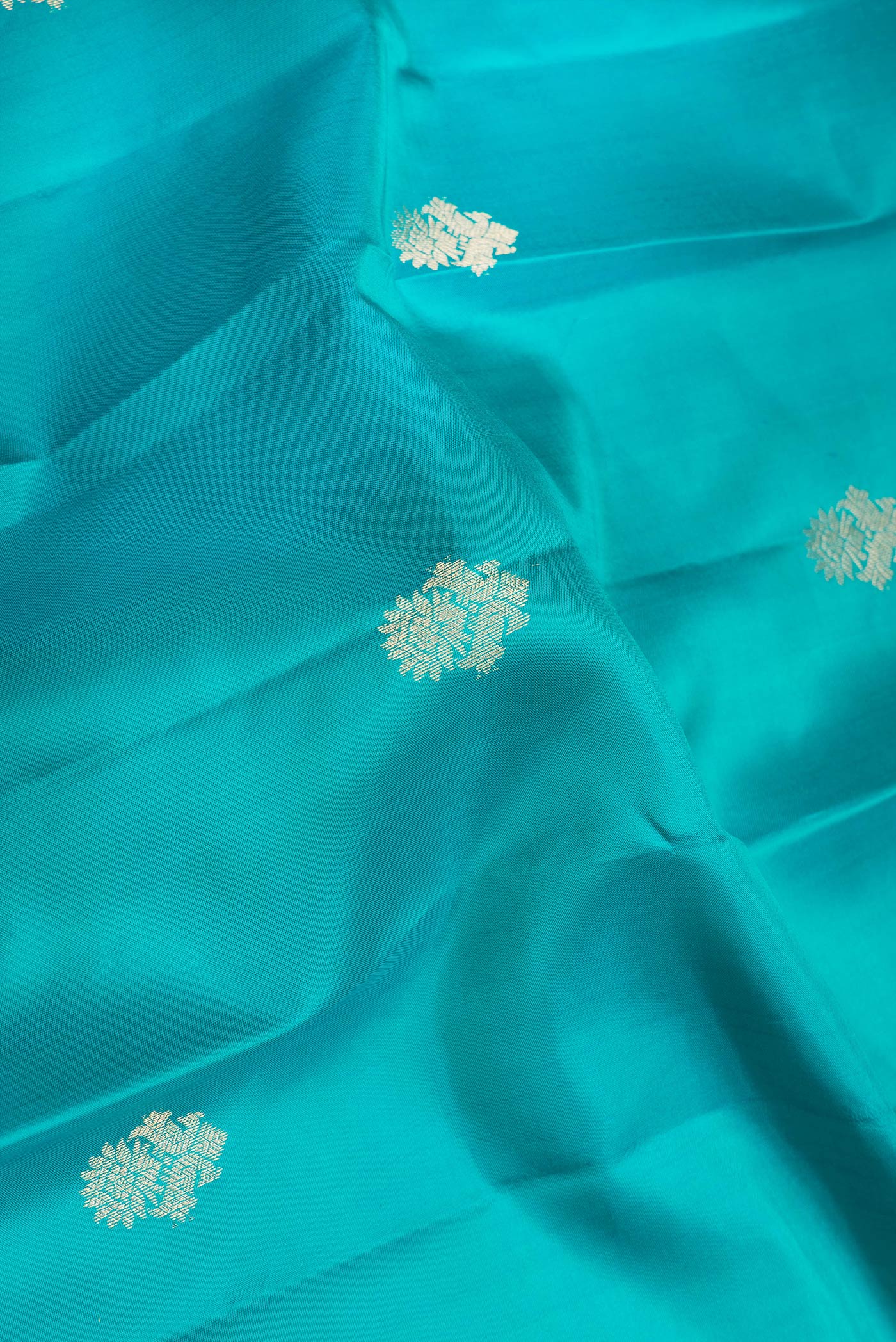 Close up of Green Dual Tone Kanjivaram Silk Saree with Zari Butta on the body and Zari Border.  displaying folds