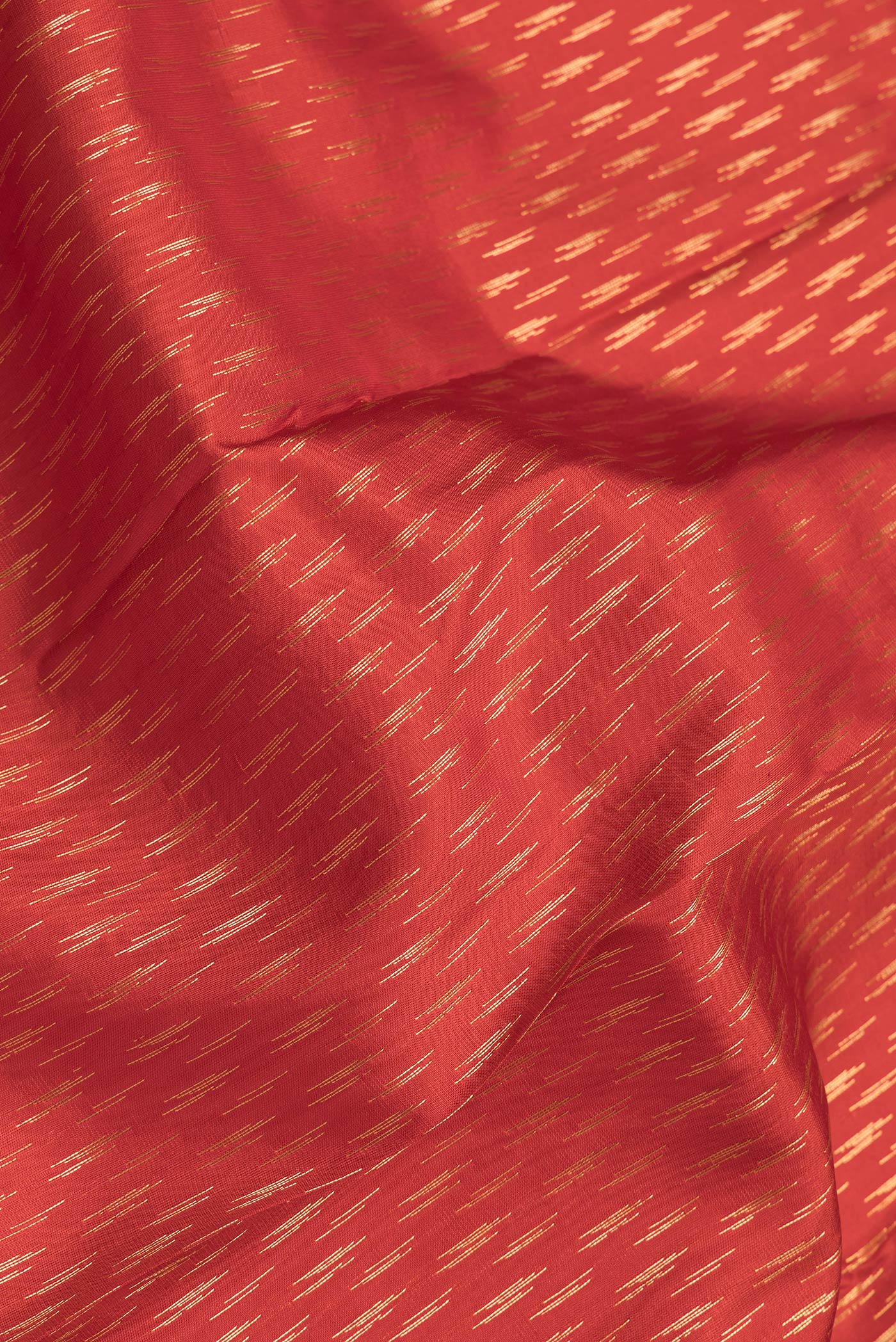 Close up of Orange Dual Tone Kanchipuram Silk Saree with Zari Butta on the body and Zari Border.  displaying folds