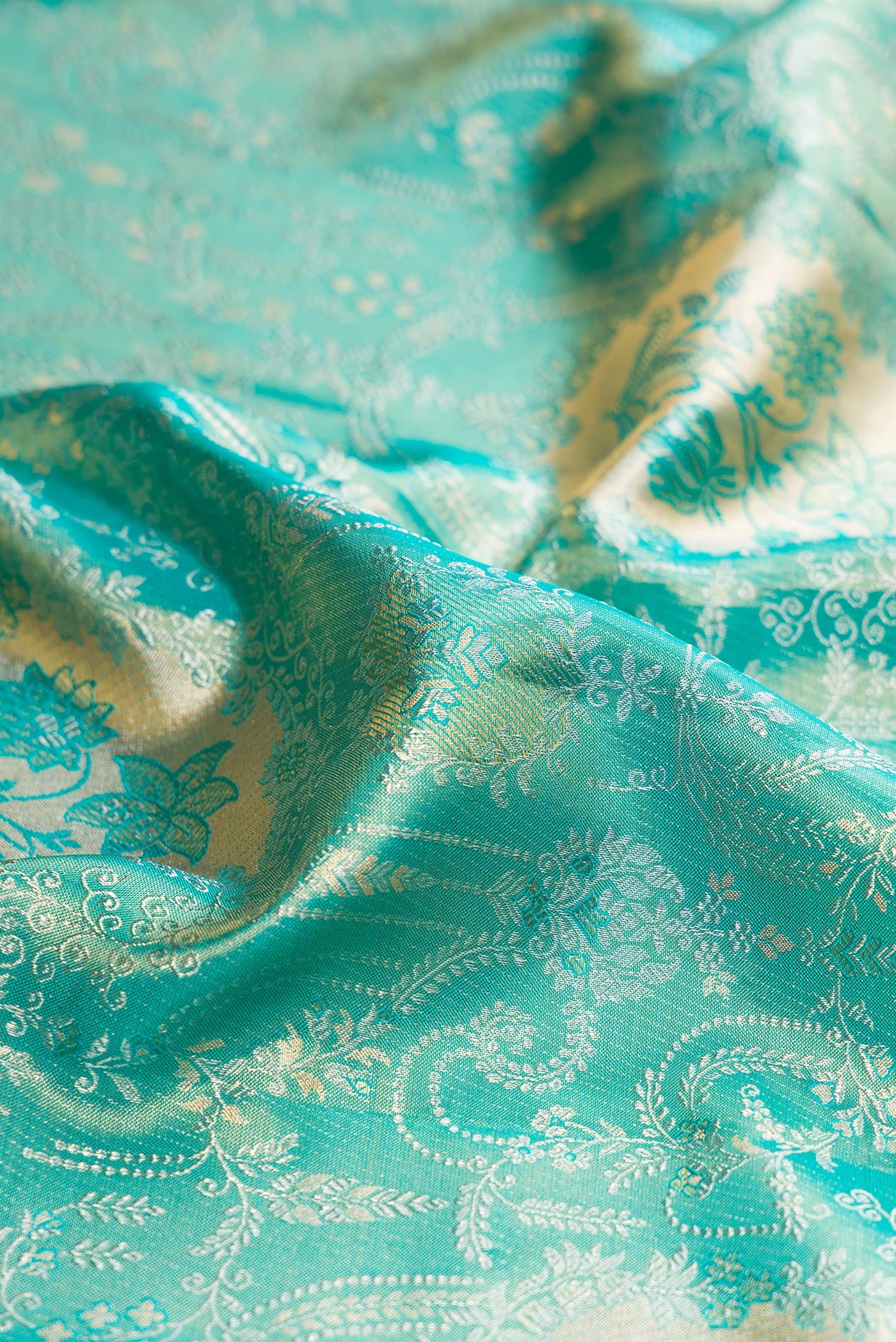 Close up of Turquoise Dual Tone Kanchipuram Tissue Silk Saree with Zari Brocade on the body and Zari Border.  displaying folds