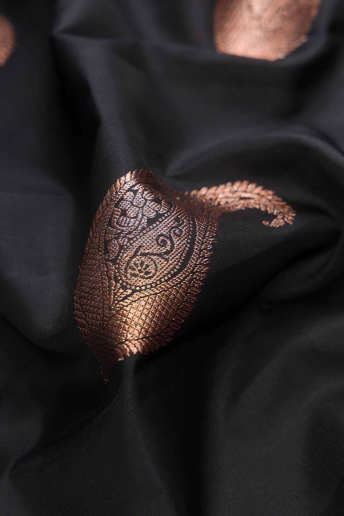 Close up of Pure Silk Pure Zari Black Dual Tone Kanchipuram Saree with Zari Butta on the body and Fancy Border.  displaying folds