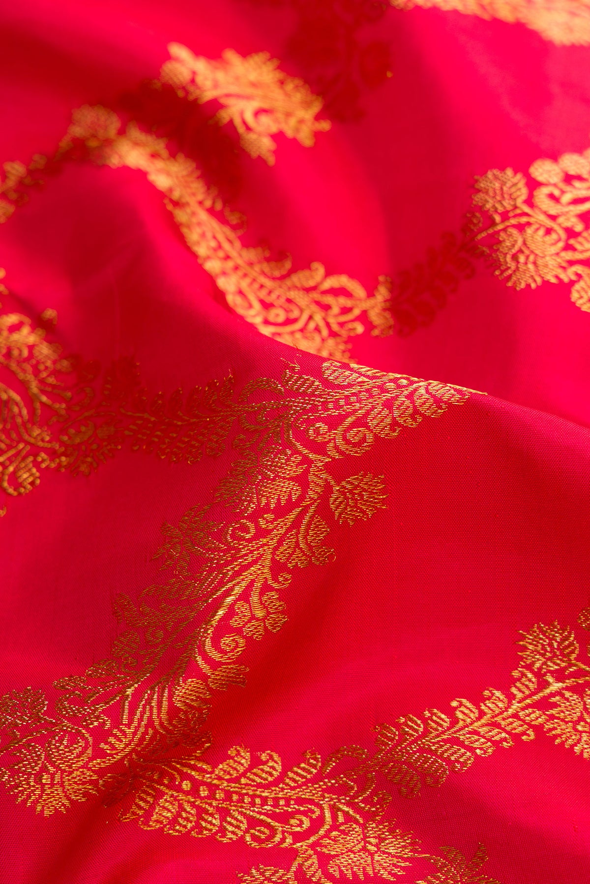 Close up of Dark Pink Dual Tone Kanjivaram Silk Saree with Zari Butta on the body and Zari Border.  displaying folds