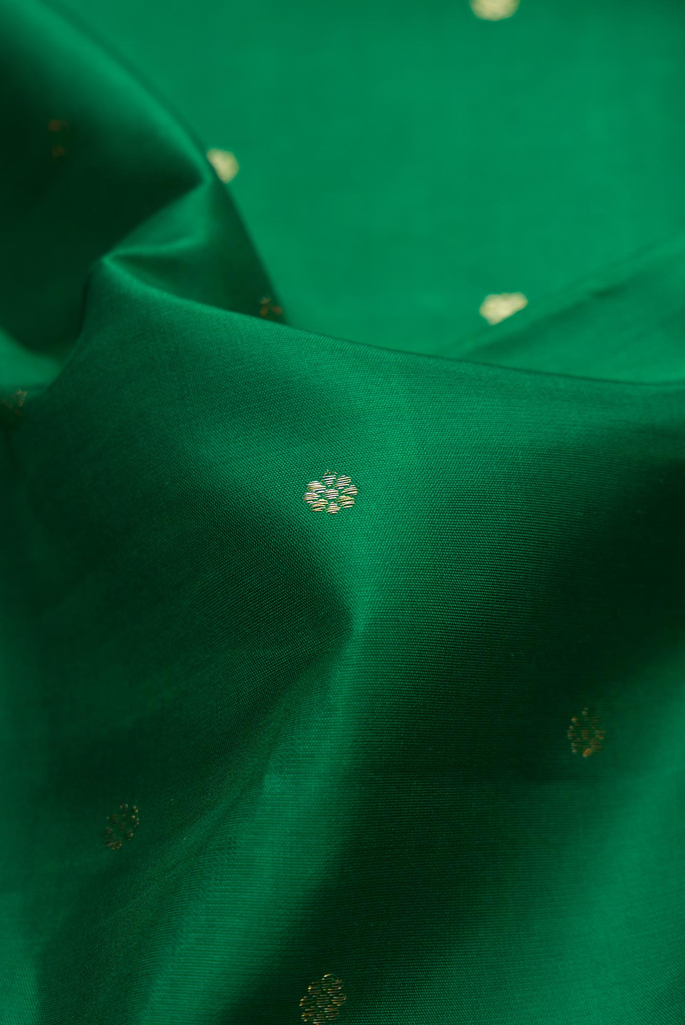 Close up of Green Dual Tone Kanchipuram Silk Saree with Zari Butta on the body and Zari Border.  displaying folds