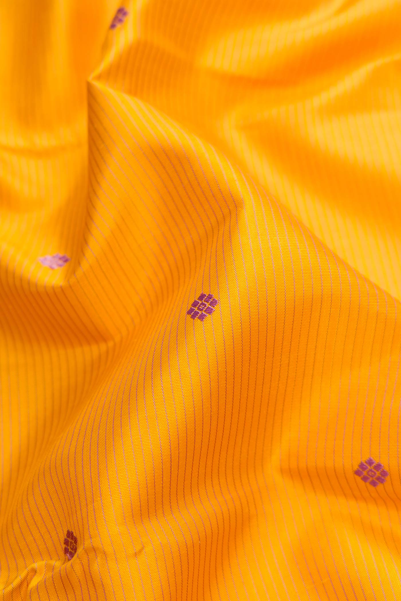 Close up of Pure Silk Pure Zari Mustard Dual Tone Kanchipuram Saree with Thread Butta on the body and Zari Border.  displaying folds