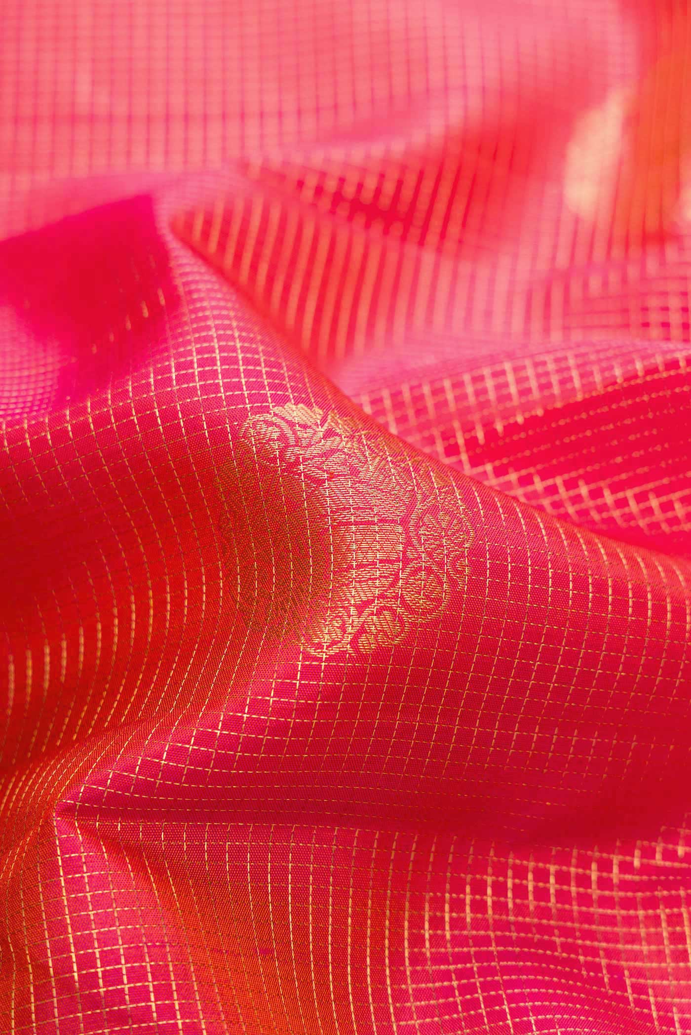 Close up of Coral Dual Tone Kanjivaram Silk Saree with Zari Butta on the body and Zari Border.  displaying folds