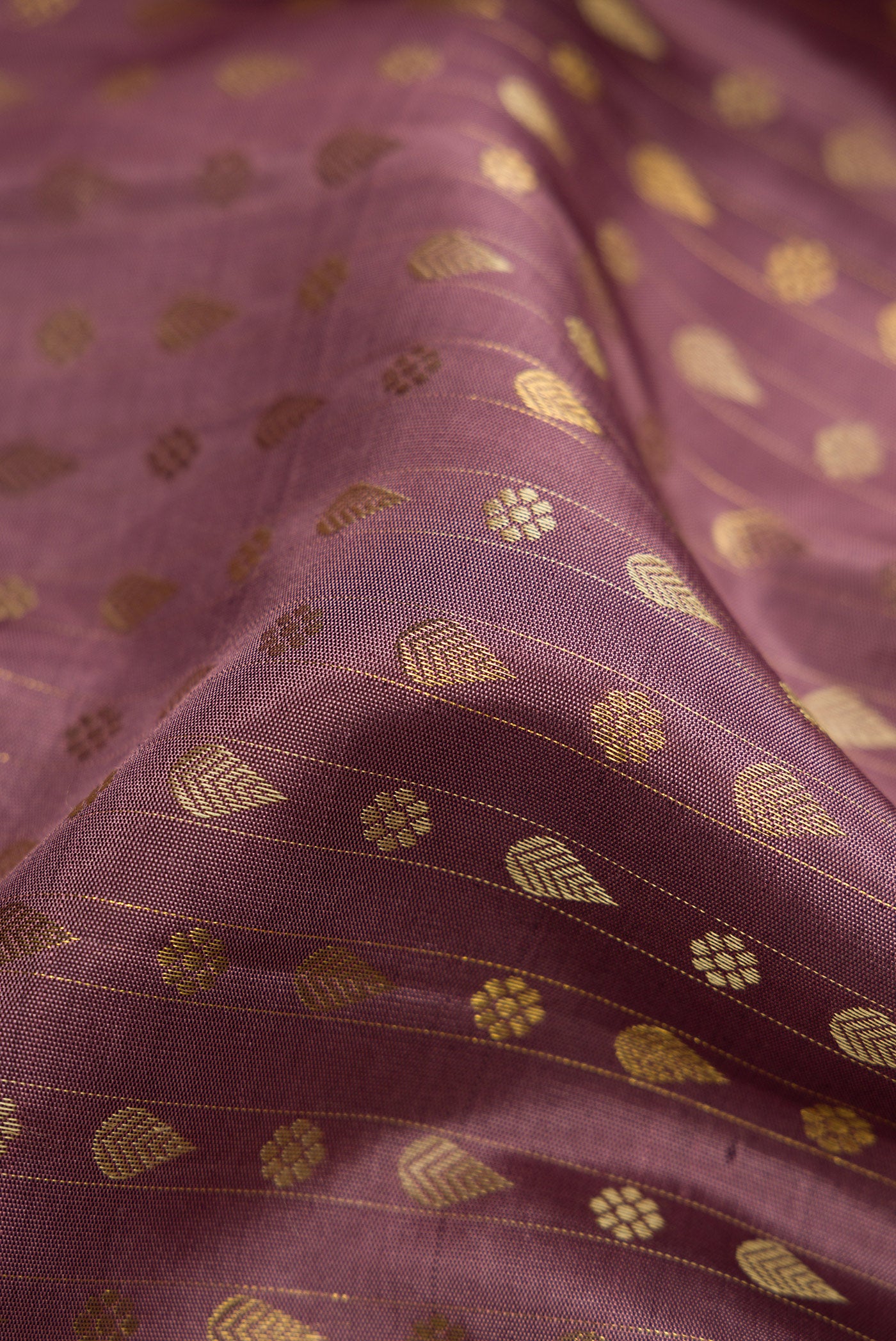 Close up of Pure Silk Pure Zari Brown Dual Tone Kanchipuram Saree with Zari And Thread Butta on the body and Zari Border.  displaying folds