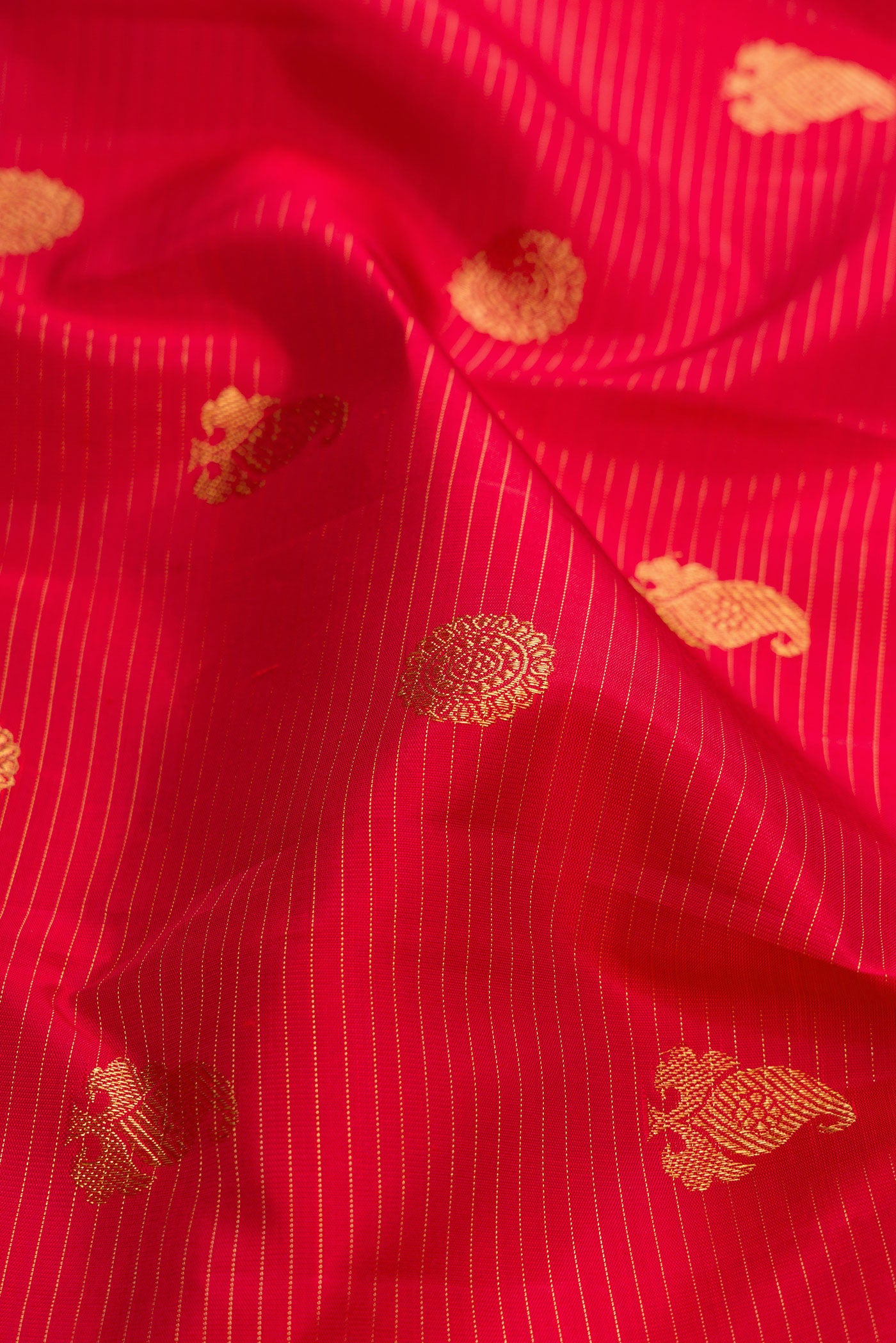 Close up of Pure Silk Pure Zari Red Dual Tone Kanchipuram Saree with Zari Butta on the body and Zari Border.  displaying folds