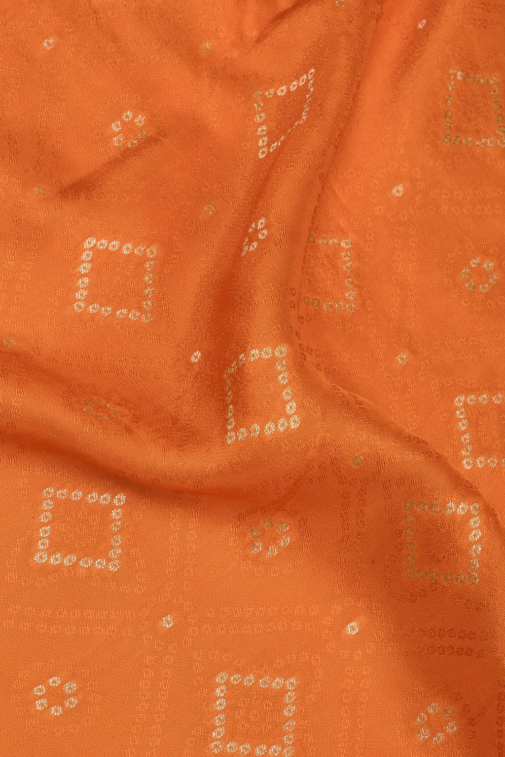Close up of Orange Dual Tone Blended Banarasi Silk Saree with Bandhani Print on the body and Zari Border.  displaying folds