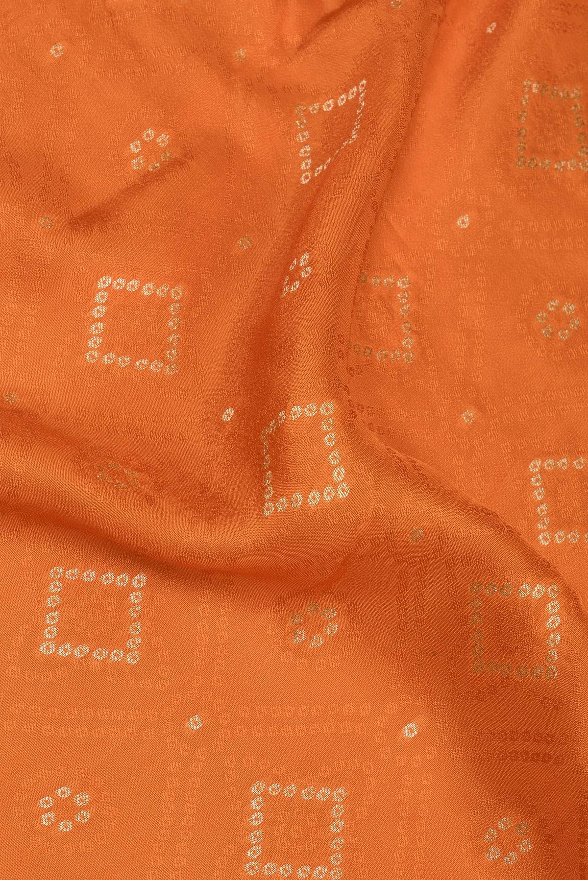 Close up of Orange Dual Tone Blended Banarasi Silk Saree with Bandhani Print on the body and Zari Border.  displaying folds