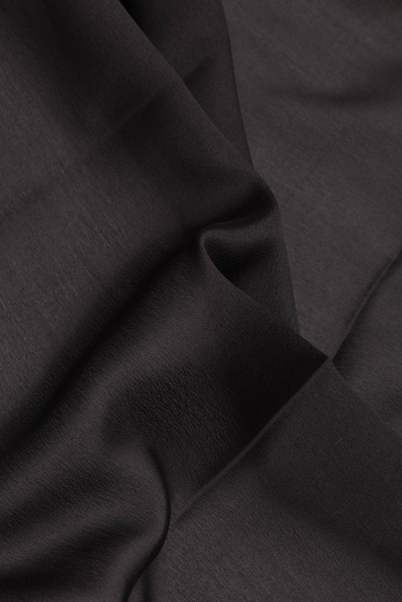 Close up of Black Dual Tone Mysore Silk Saree with Plain Body and Zari Border.  displaying folds