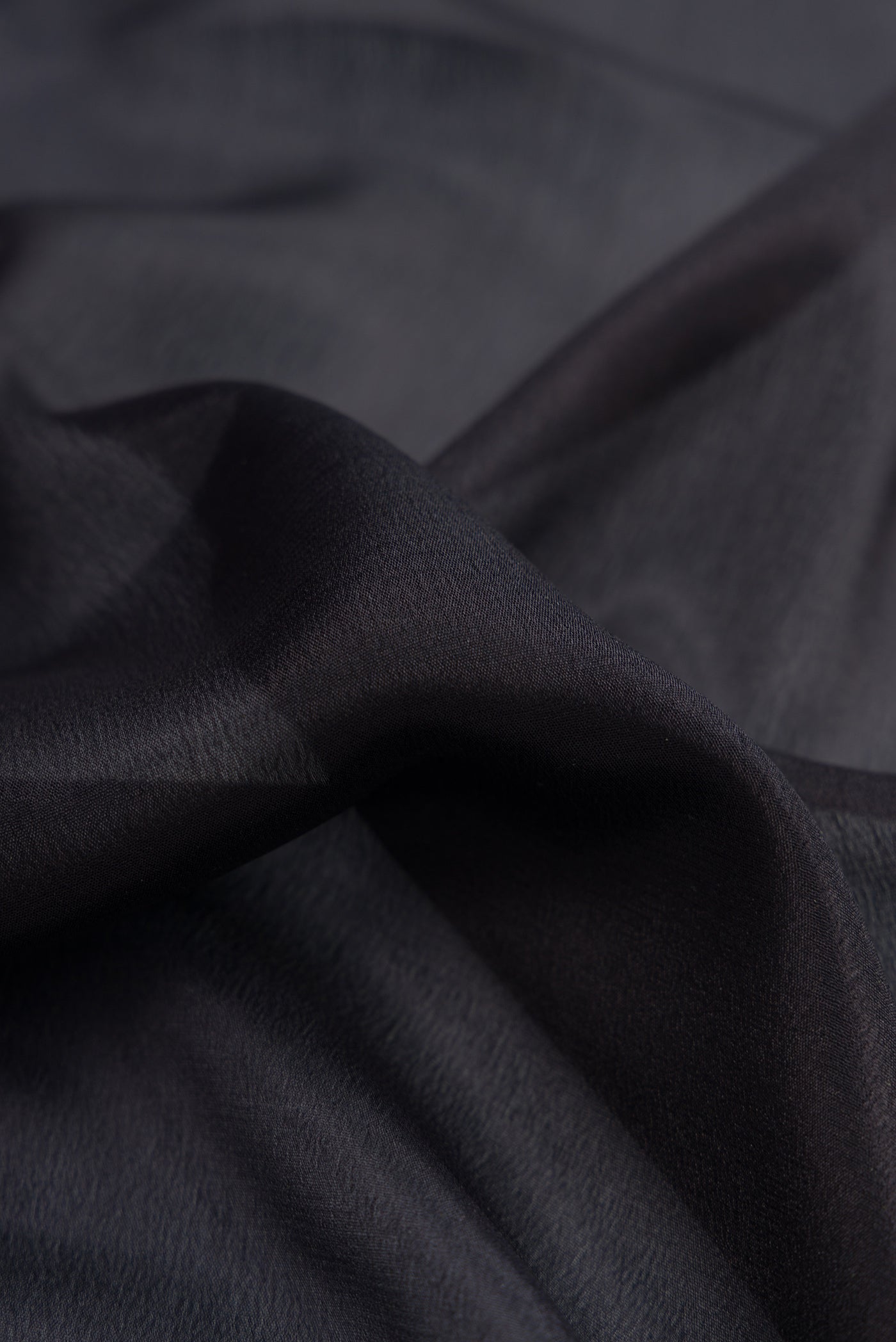 Close up of Black Mysore Crepe Saree with Plain Body and Zari Border.  displaying folds