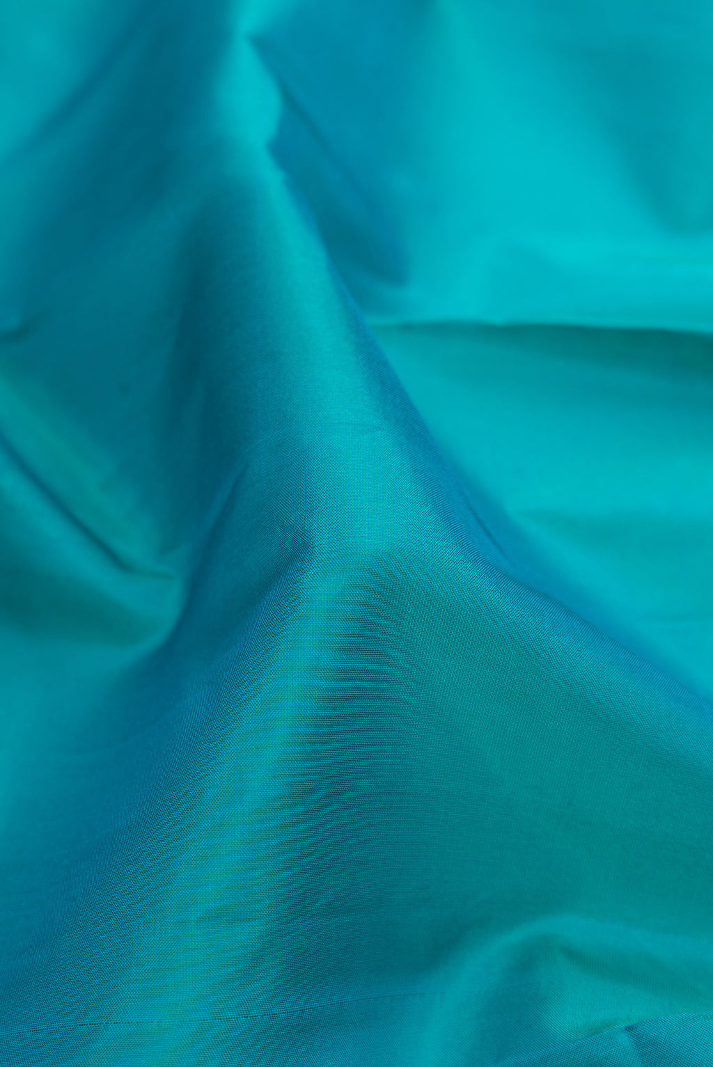 Close up of Peacock Blue Dual Tone Soft Silk Saree with Plain Body and Fancy Border.  displaying folds