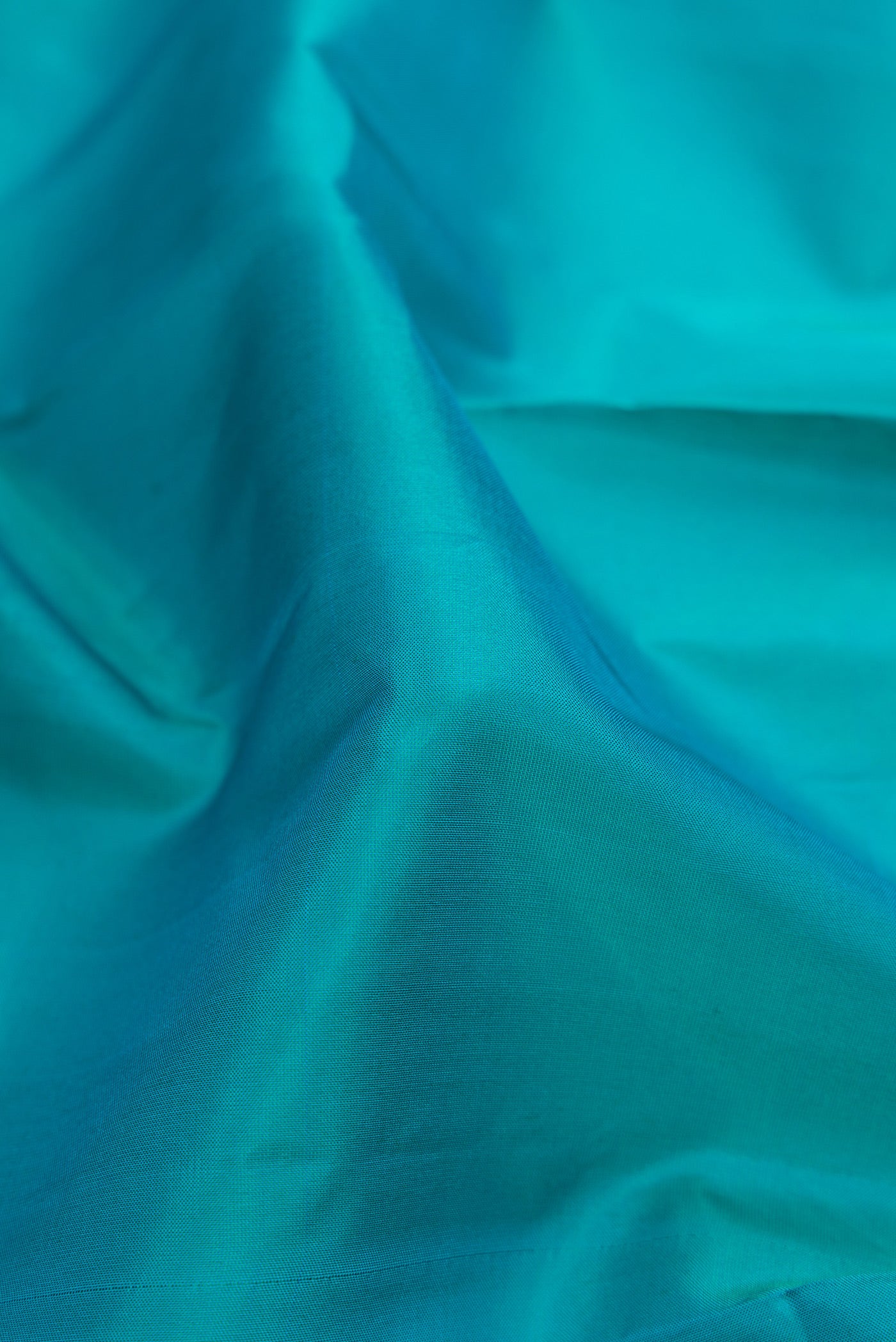 Close up of Peacock Blue Dual Tone Soft Silk Saree with Plain Body and Fancy Border.  displaying folds