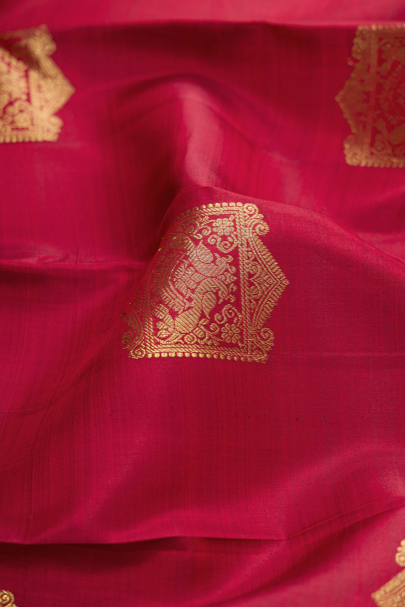 Close up of Maroon Dual Tone Kanjivaram Silk Saree with Zari Butta on the body and Zari Border.  displaying folds