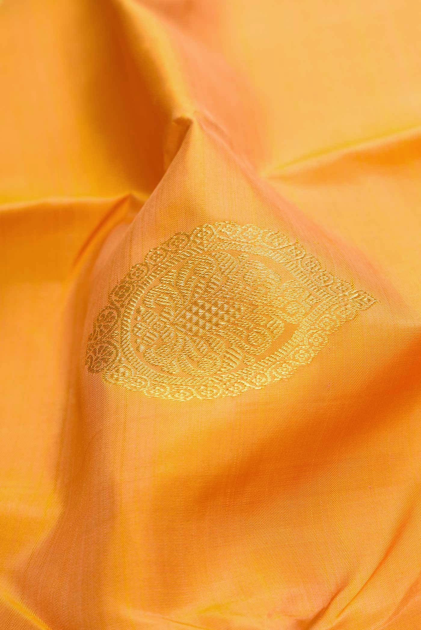 Close up of Golden Peach Dual Tone Kanjivaram Silk Saree with Zari Butta on the body and Zari Border.  displaying folds