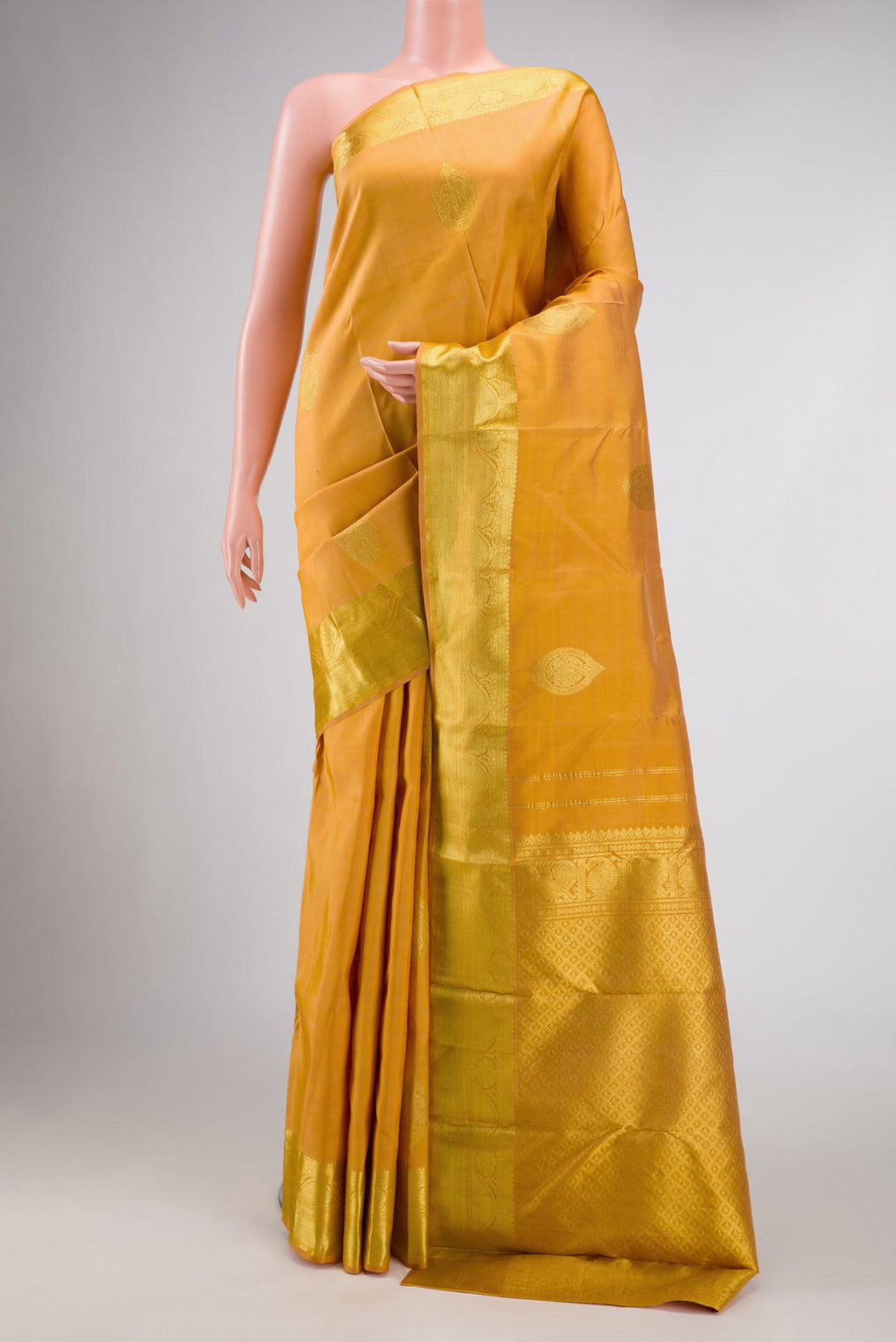 Golden Peach Dual Tone Kanjivaram Silk Saree with Zari Butta on the body and Zari Border.  displayed on a mannequin