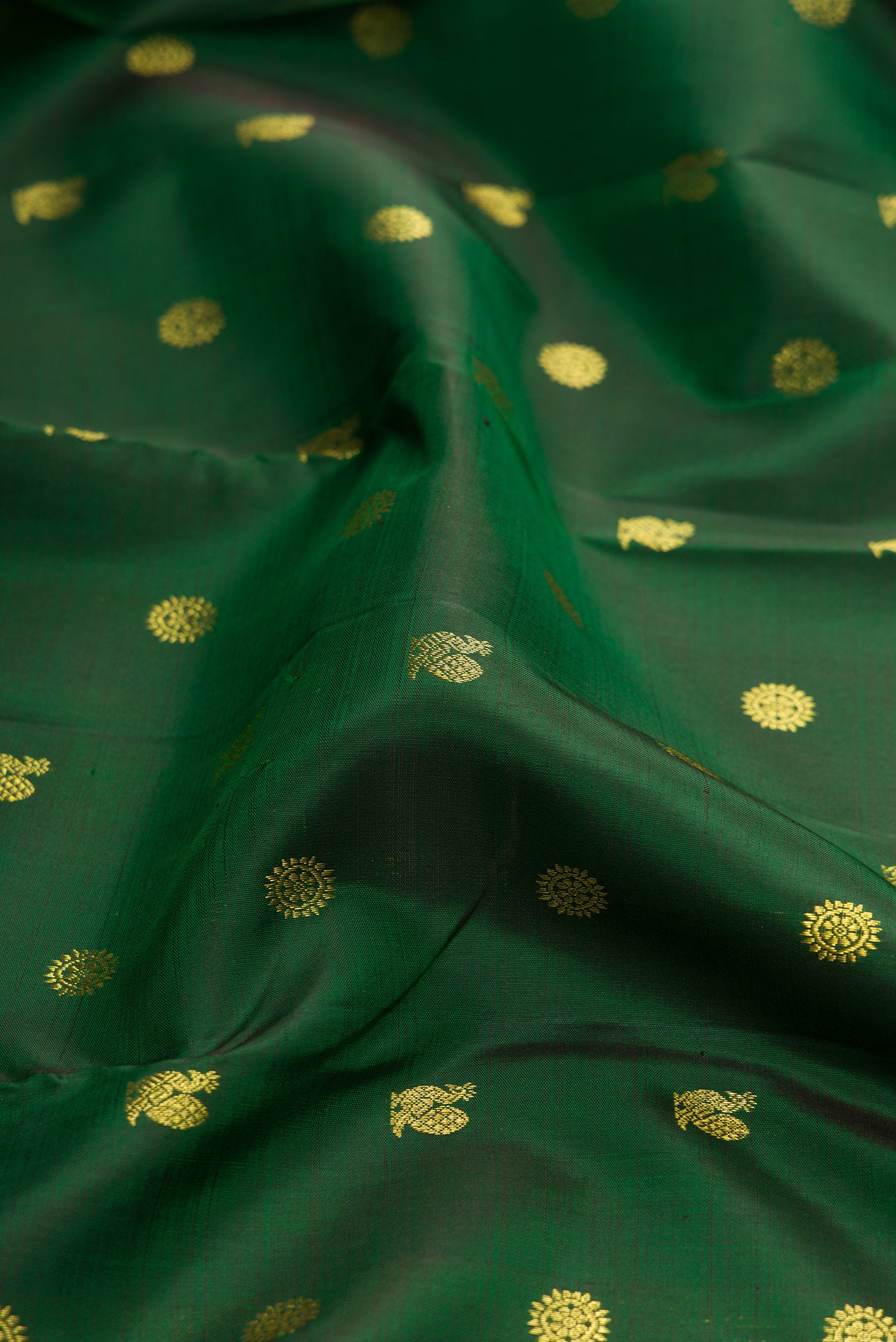 Close up of Green Dual Tone Kanjivaram Silk Saree with Zari Butta on the body and Zari Border.  displaying folds
