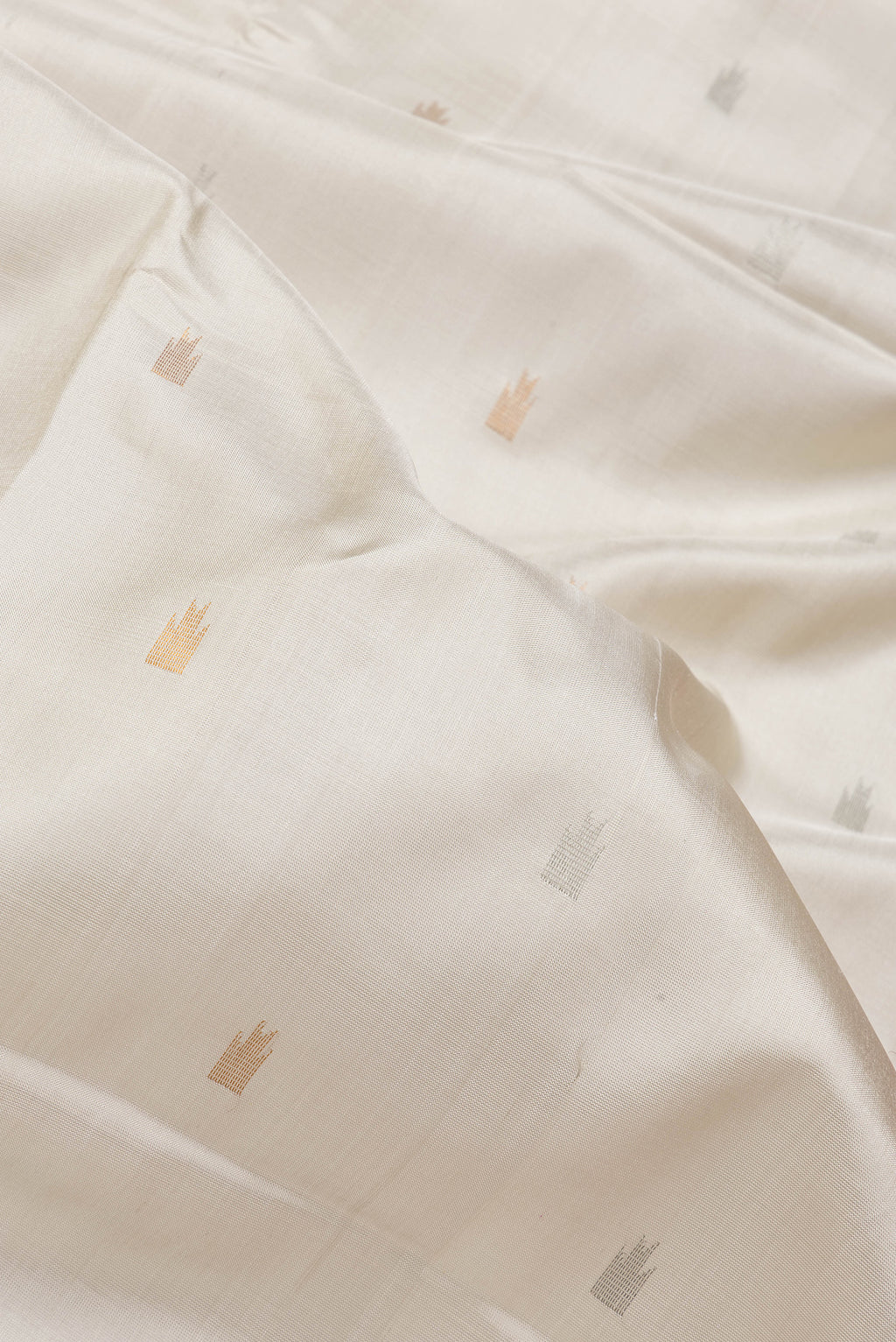 Close up of Beige Dual Tone Uppada Silk Saree with Zari Butta on the body and Temple Border.  displaying folds