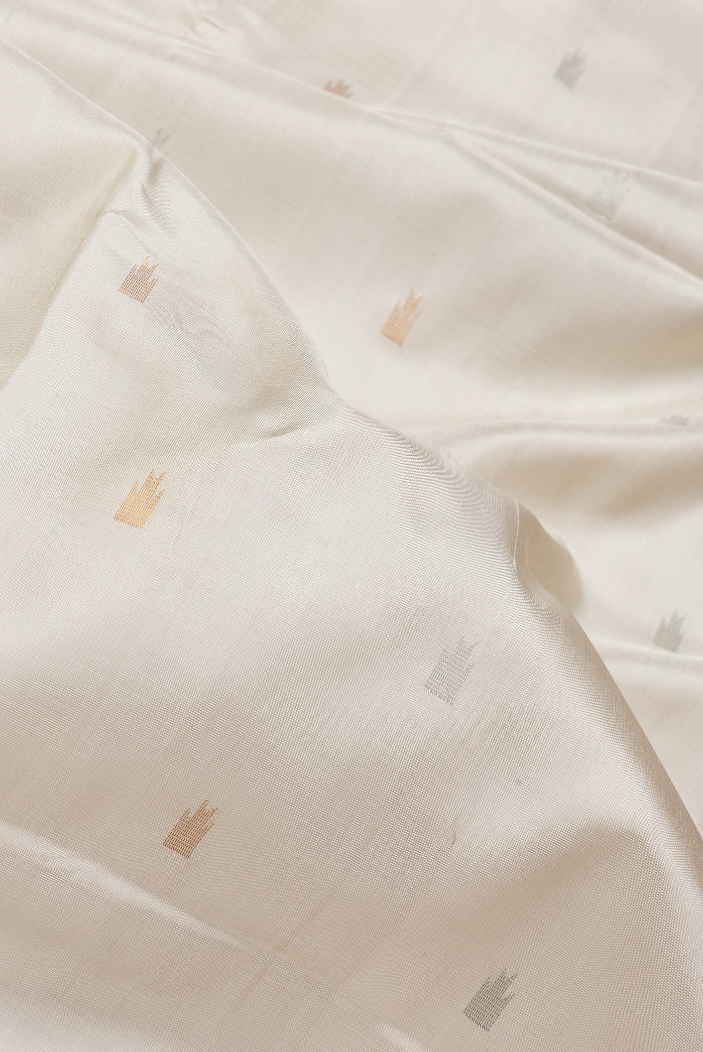Close up of Beige Dual Tone Uppada Silk Saree with Zari Butta on the body and Temple Border.  displaying folds