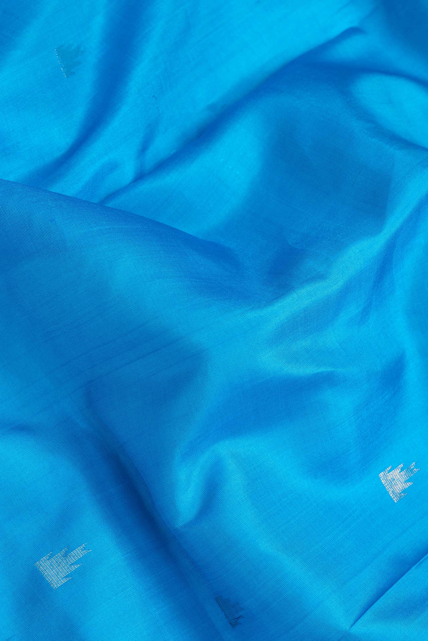 Close up of Sky Blue Dual Tone Uppada Silk Saree with Zari Butta on the body and Temple Border.  displaying folds