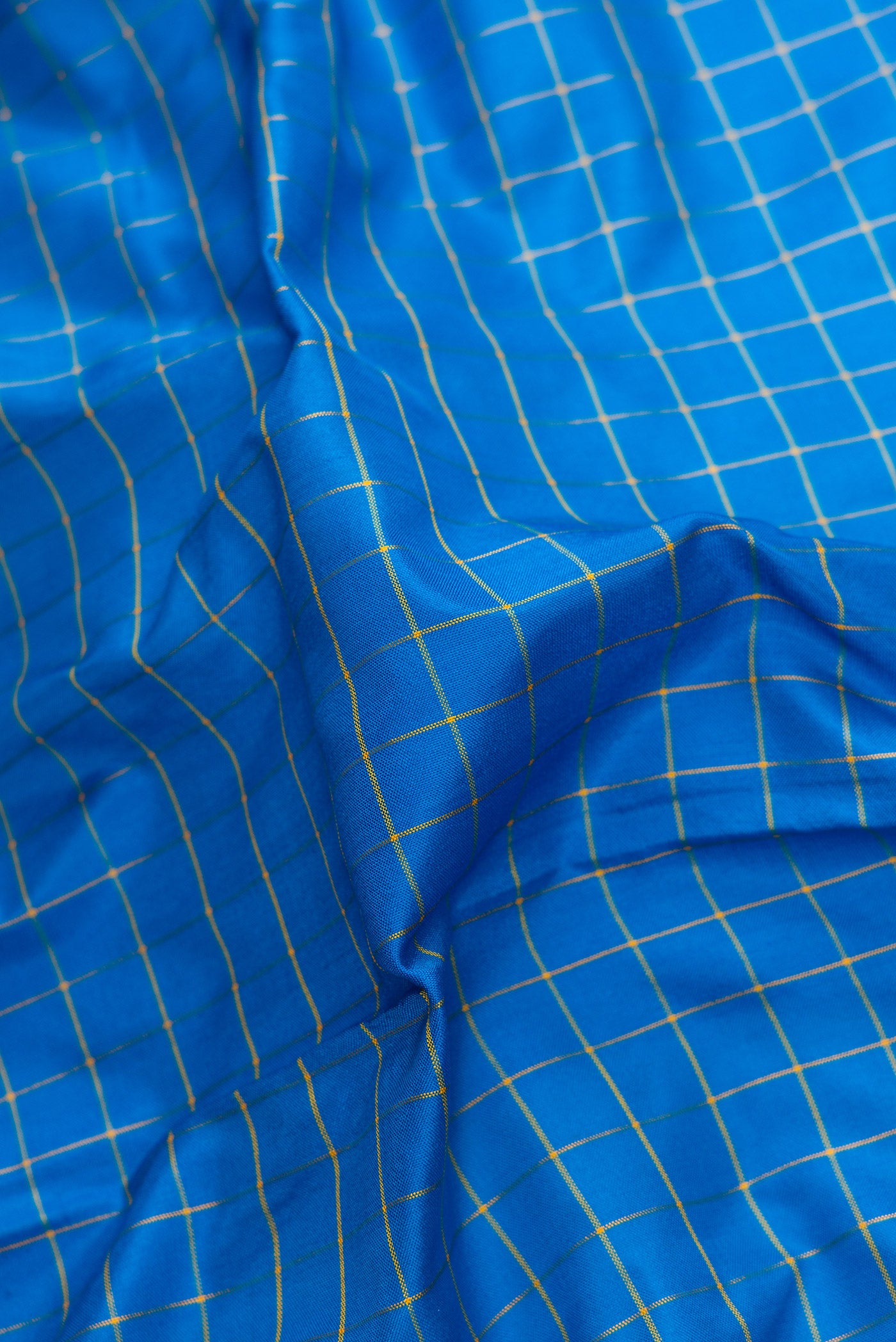 Close up of Peacock Blue Dual Tone Soft Silk Saree with Checked design on the body and Zari Border.  displaying folds