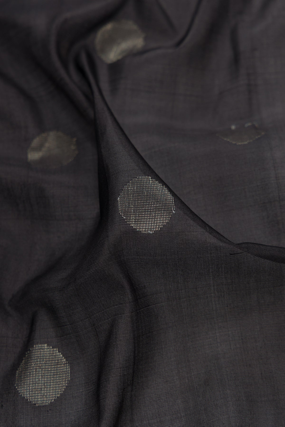 Close up of Black Dual Tone Uppada Silk Saree with Zari Butta on the body and Zari Border.  displaying folds
