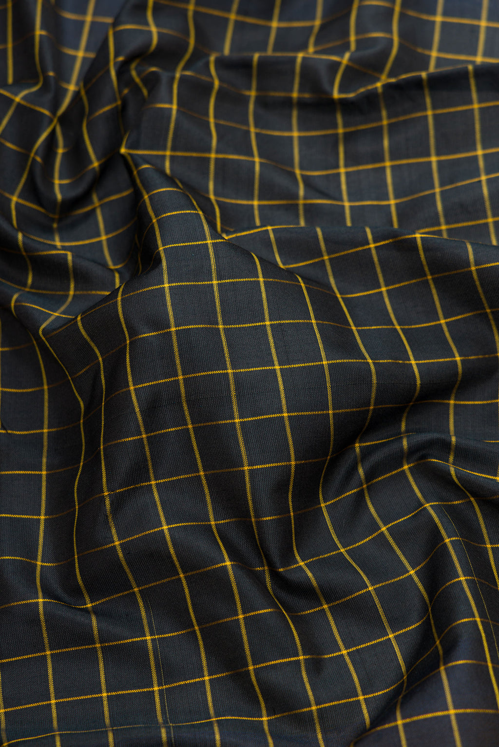 Close up of Black Dual Tone Uppada Silk Saree with Checked design on the body and Zari Border.  displaying folds