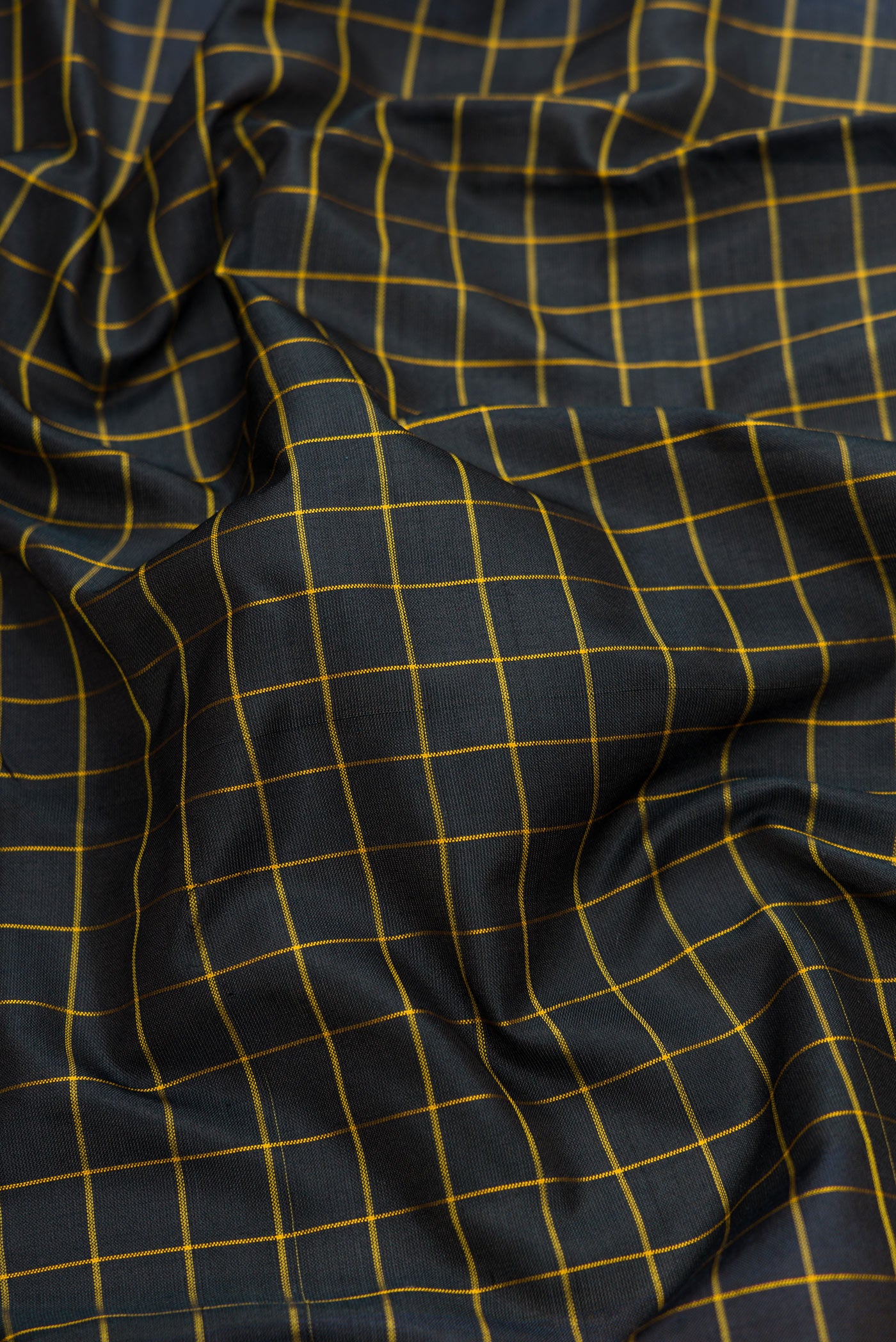Close up of Black Dual Tone Uppada Silk Saree with Checked design on the body and Zari Border.  displaying folds