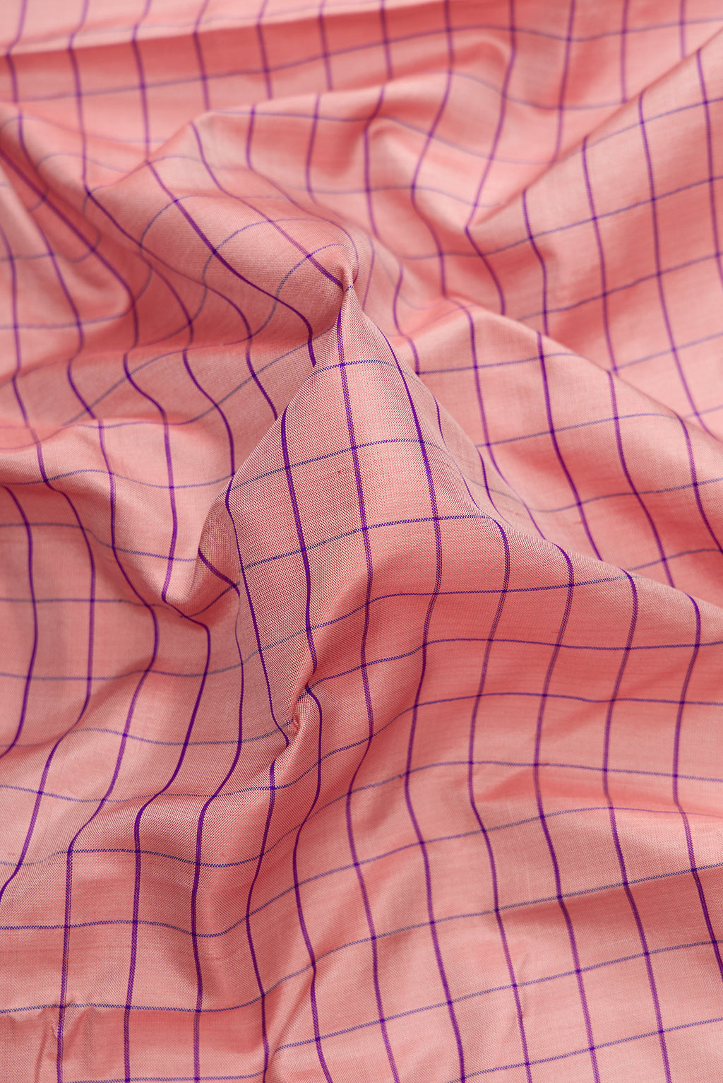 Close up of Rose Gold Dual Tone Uppada Silk Saree with Checked design on the body and Zari Border.  displaying folds