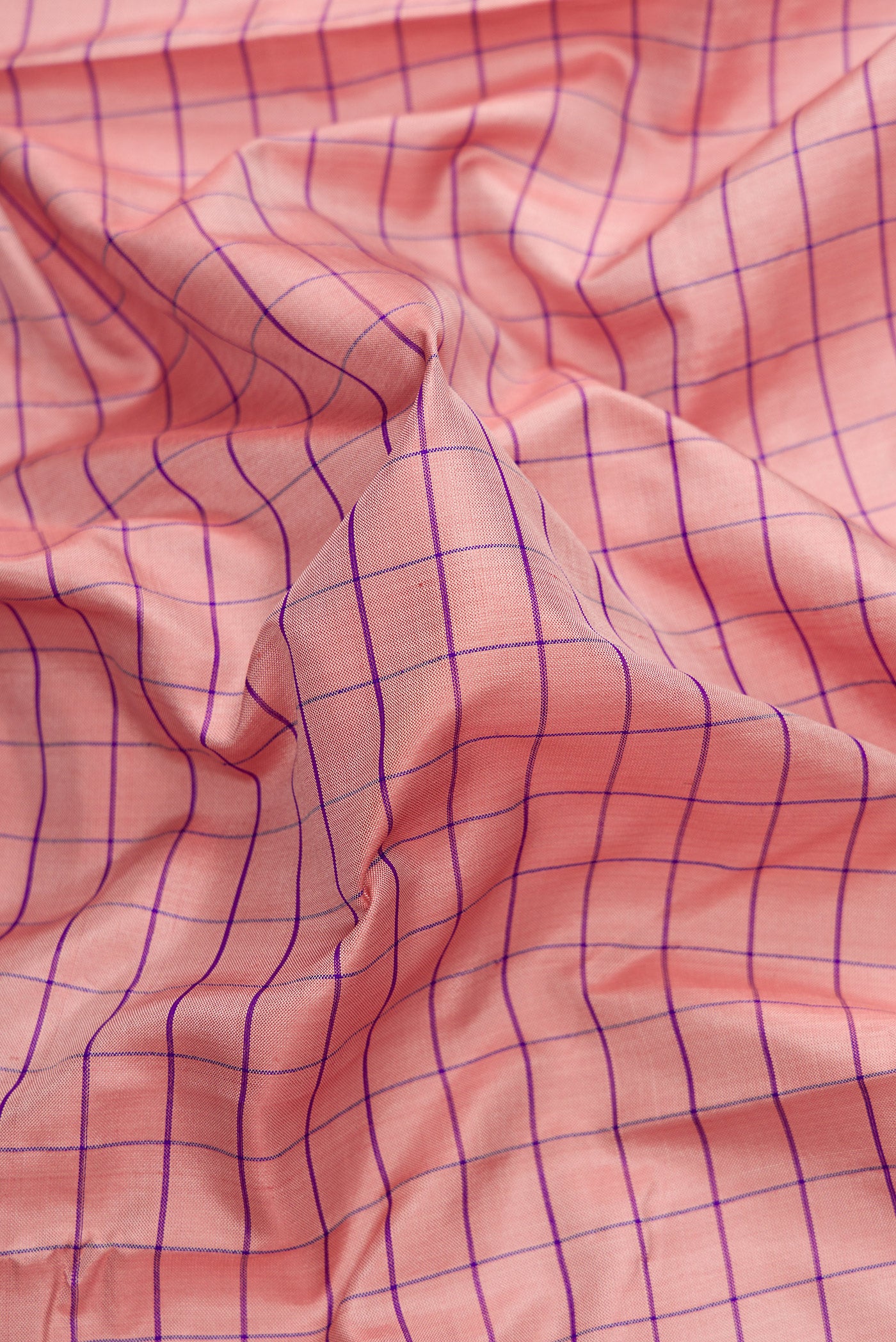 Close up of Rose Gold Dual Tone Uppada Silk Saree with Checked design on the body and Zari Border.  displaying folds