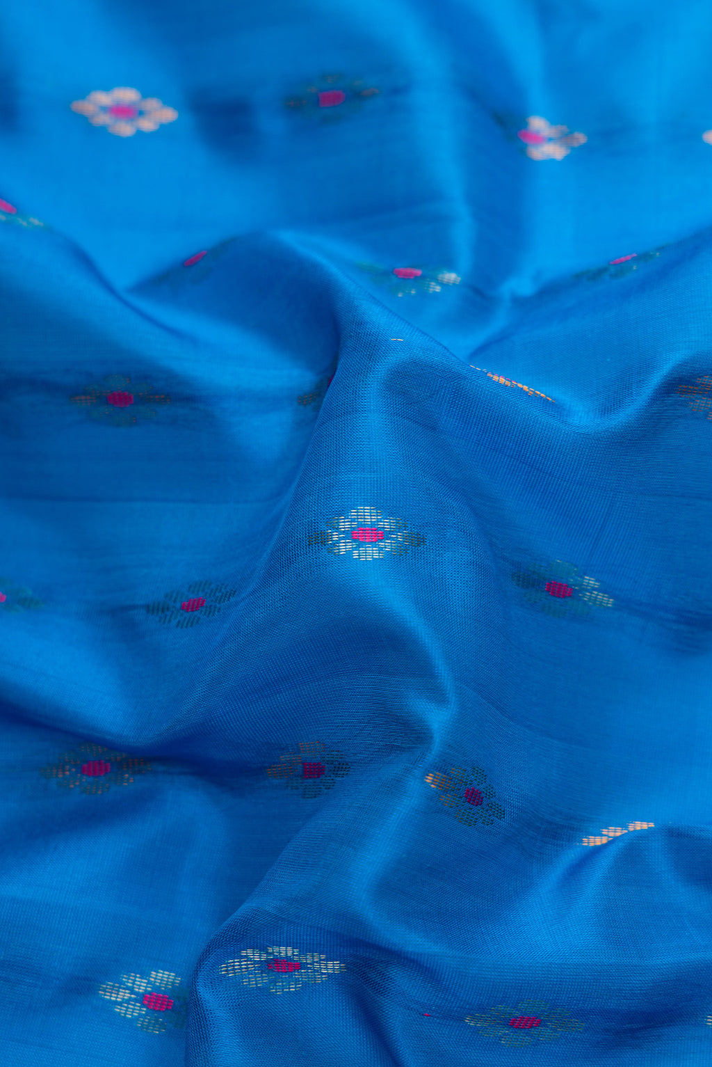 Close up of Sky Blue Dual Tone Uppada Silk Saree with Zari And Thread Butta on the body and Zari Border.  displaying folds