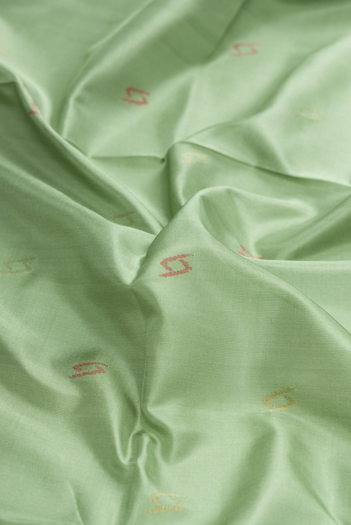 Close up of Pista Green Dual Tone Uppada Silk Saree with Zari And Thread Butta on the body and Zari Border.  displaying folds