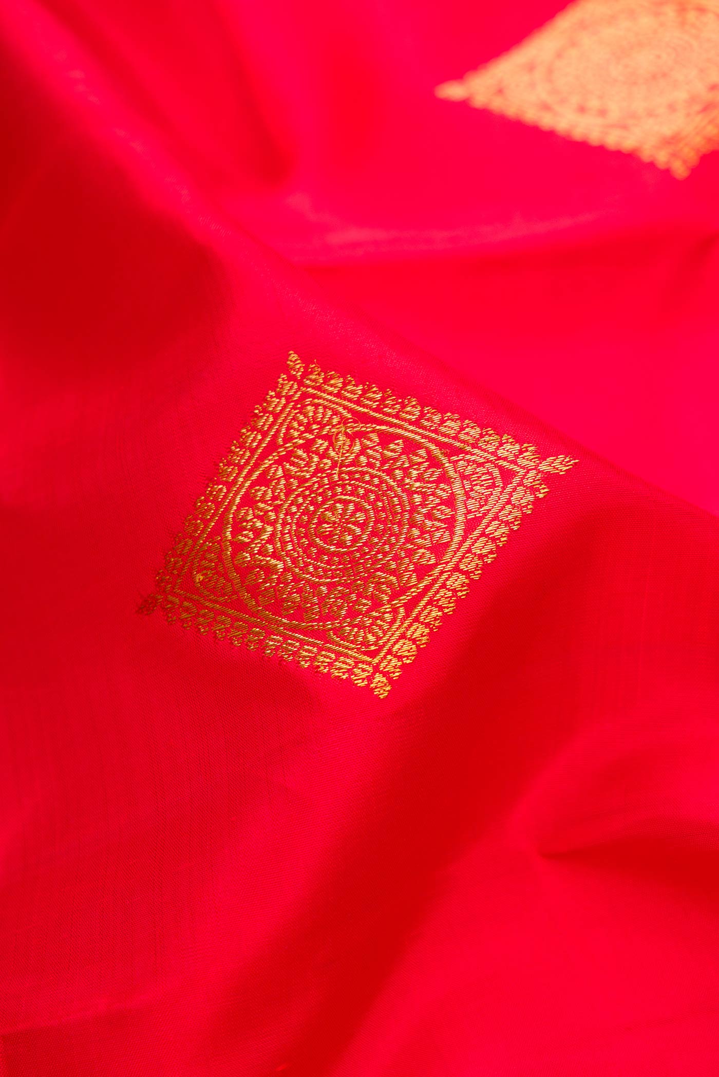 Close up of Red Dual Tone Kanjivaram Silk Saree with Zari Butta on the body and Zari Border.  displaying folds
