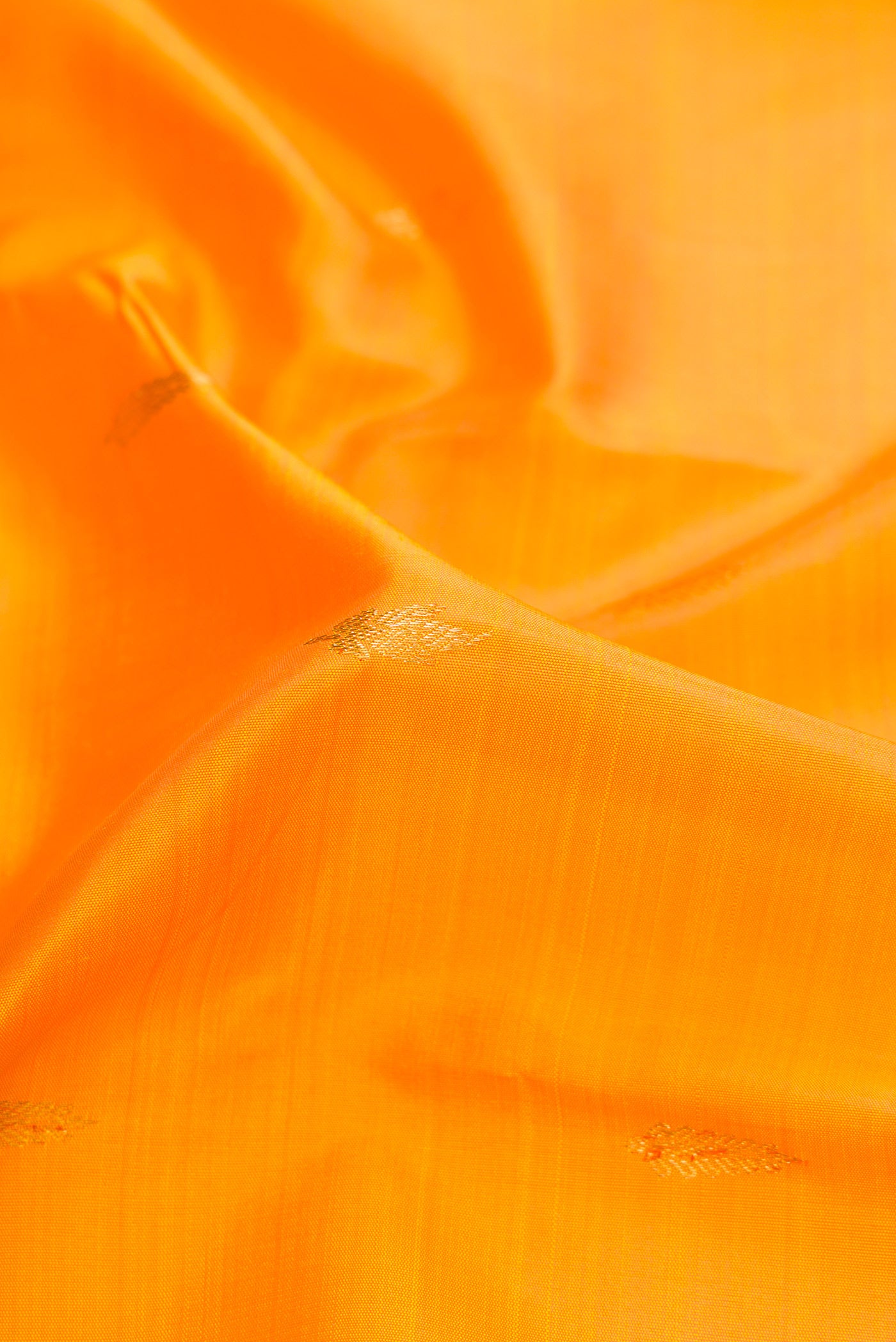 Close up of Pure Silk Pure Zari Orange Dual Tone Kanjivaram Saree with Zari Butta on the body and Zari Border.  displaying folds