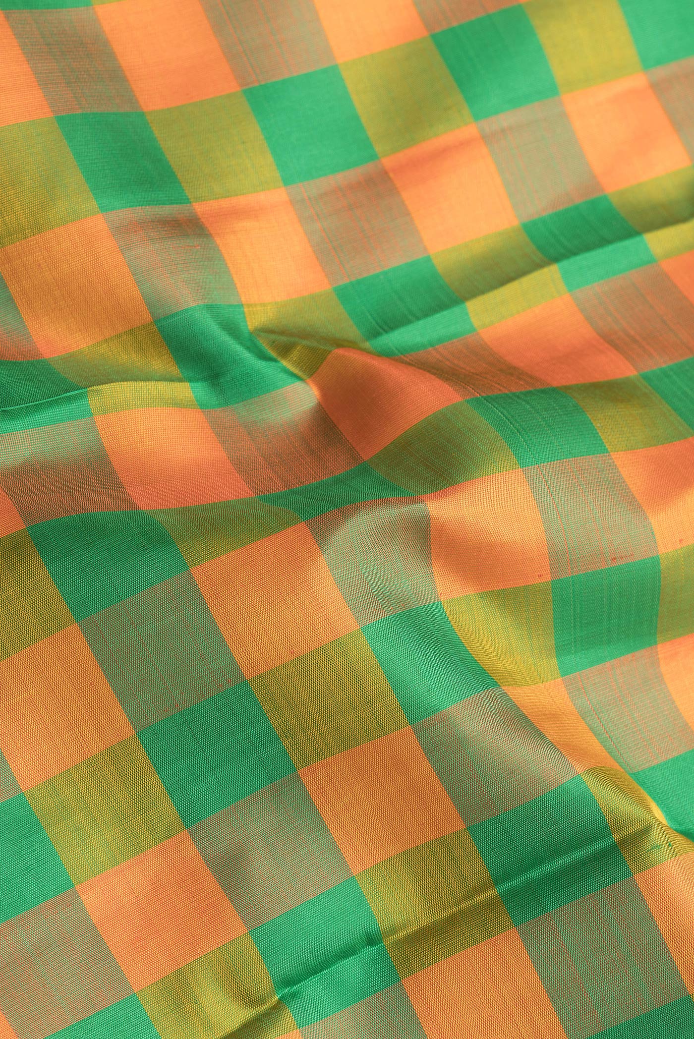 Close up of Green and Orange Color Kanjivaram Silk Saree with Checked design on the body and Zari Border.  displaying folds