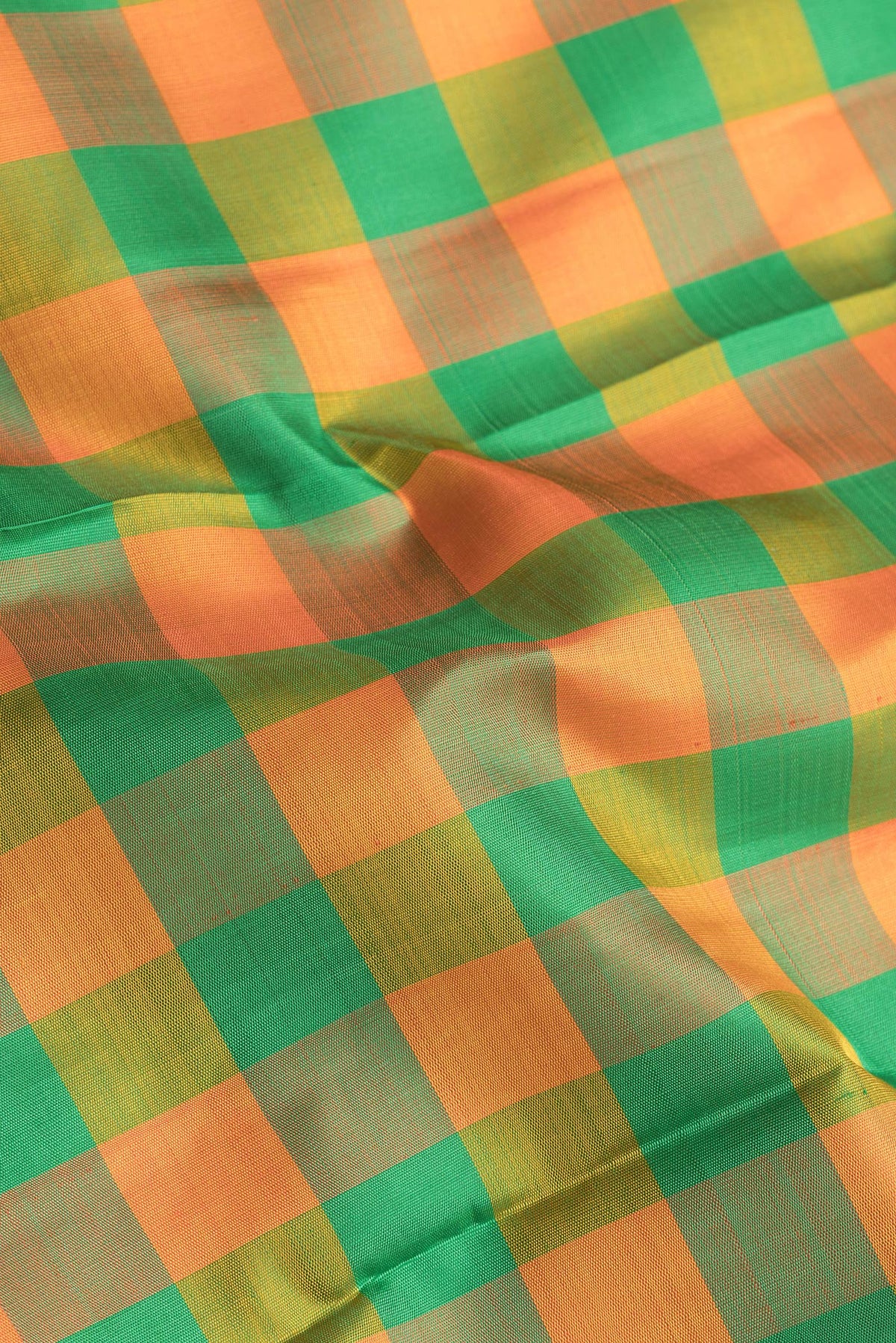 Close up of Green and Orange Color Kanjivaram Silk Saree with Checked design on the body and Zari Border.  displaying folds