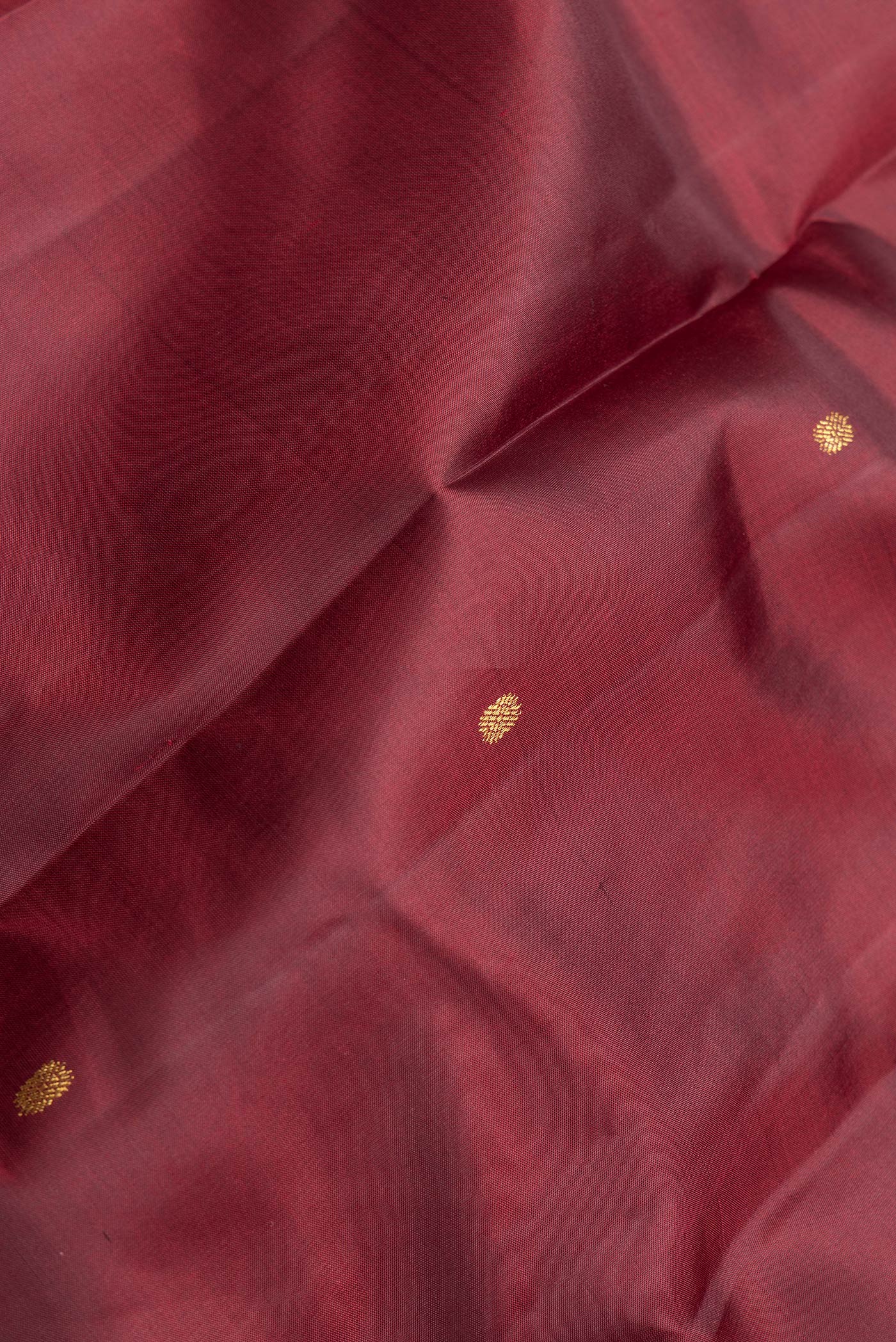 Close up of Maroon Dual Tone Kanchipuram Silk Saree with Zari Butta on the body and Zari Border.  displaying folds